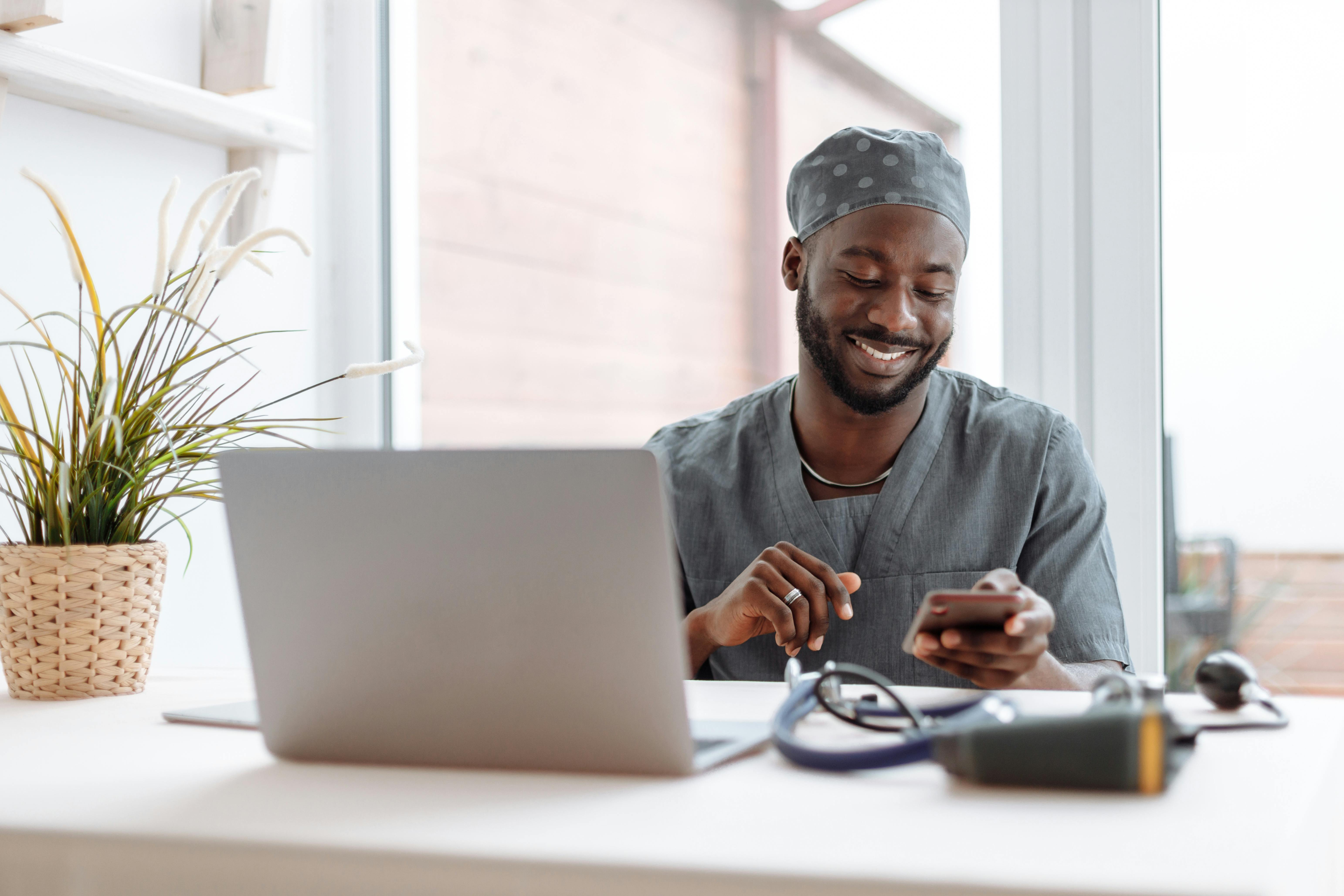 Image of Nurse wearing black scrubs taking a break from his shift on his phone