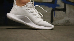 Image of Close up of white sneakers on feet of a woman, tiptoeing with a dark background.