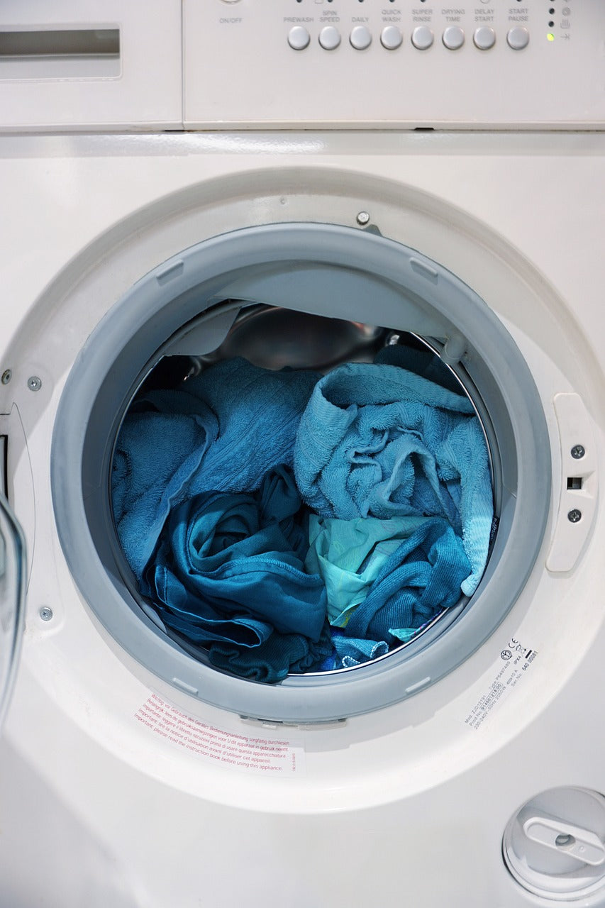 Blue medical scrubs inside a front-loading washing machine, ready for cleaning.