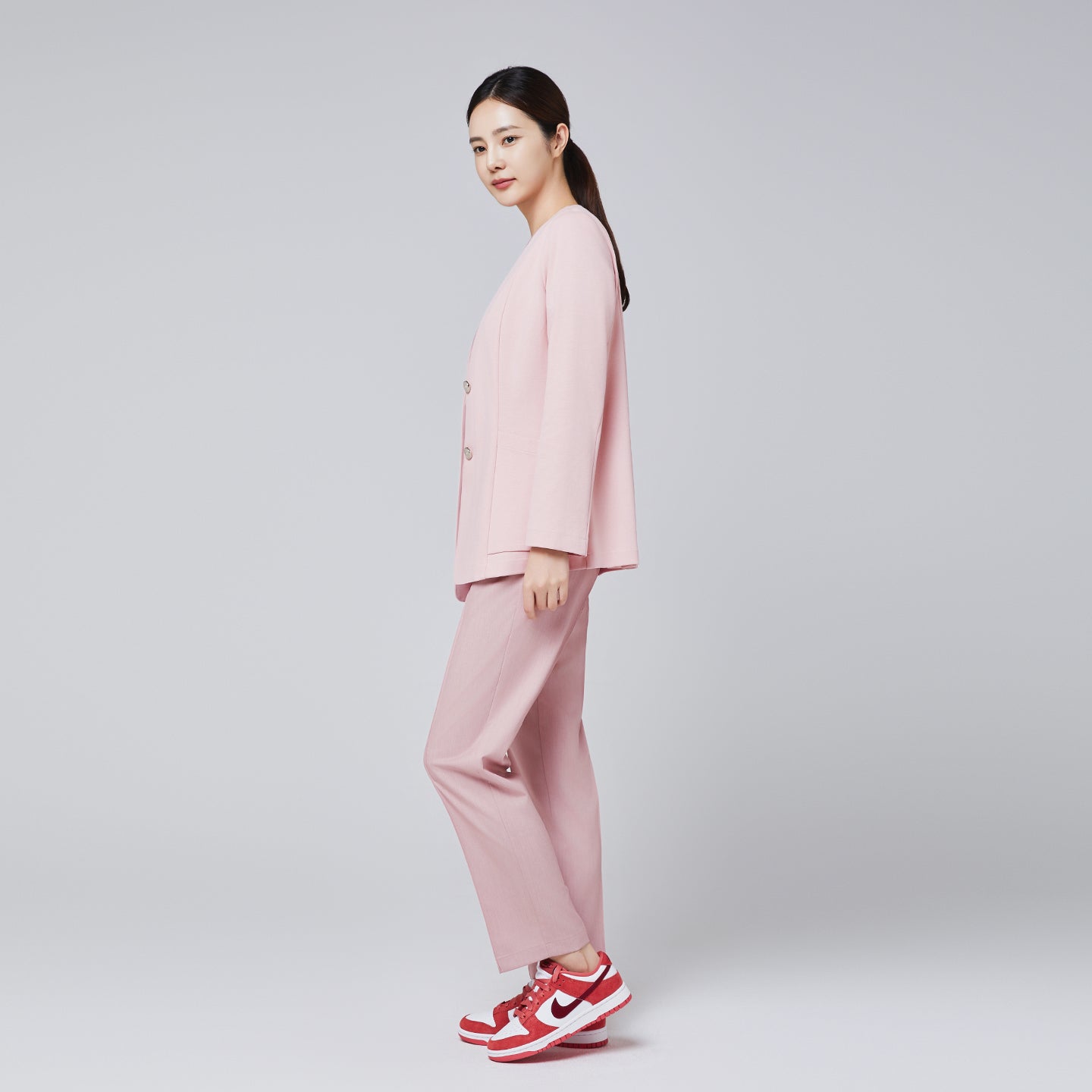 Image of A woman dressed in a soft pink comfort cardigan and matching trousers, paired with red and white sneakers, posing sideways,Soft Pink