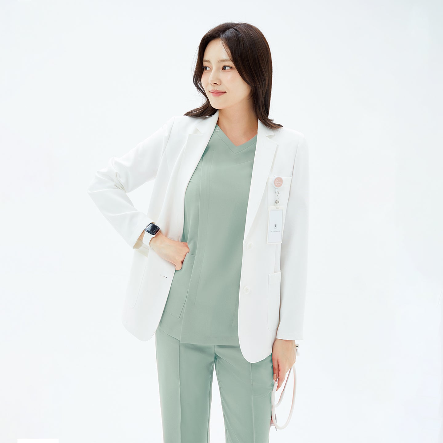 Image of White short lab coat LCW-21 styled over a light sage scrub set, featuring a clean tailored fit and practical front pockets for a polished professional look.