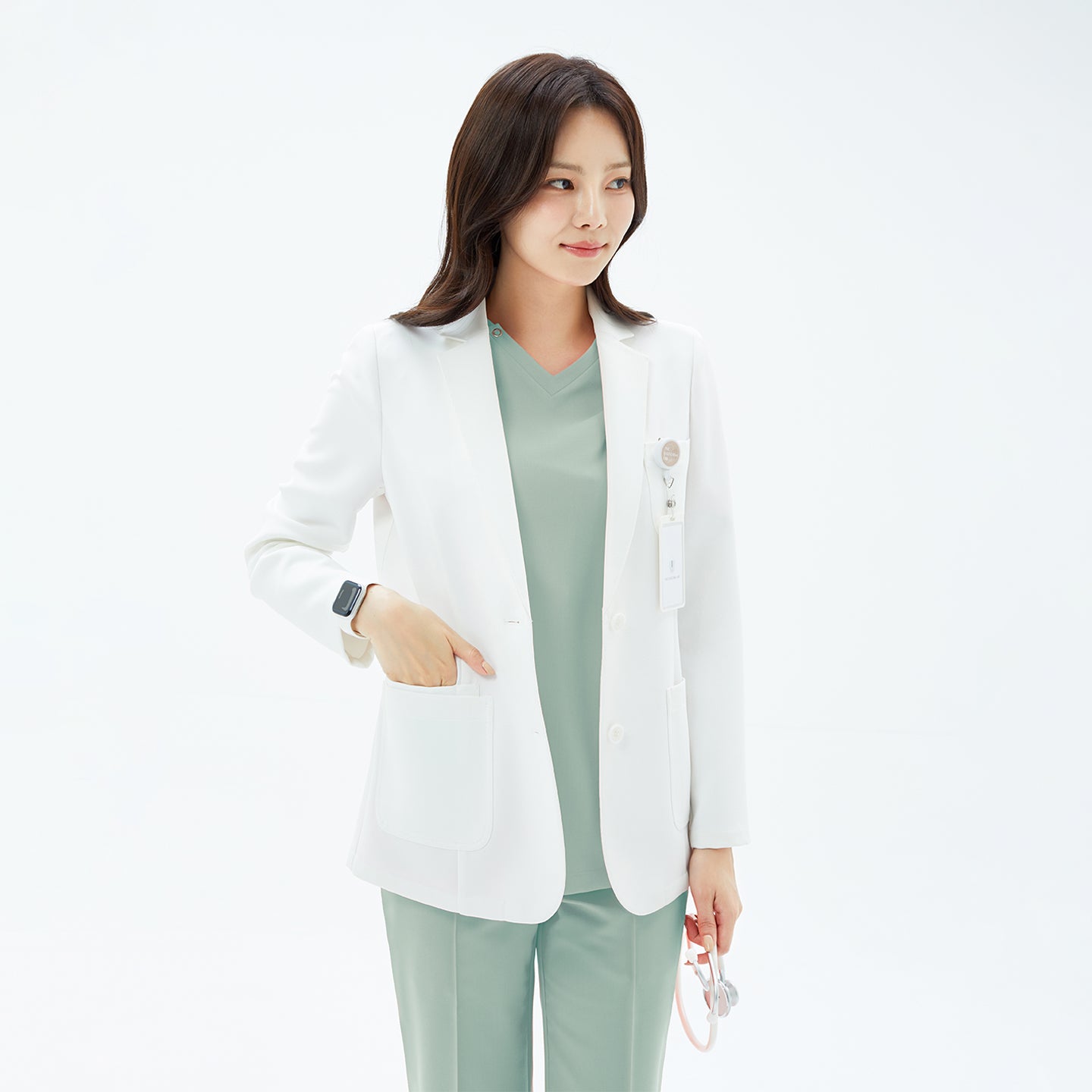 Image of White_Short_Lab_Coat_LCW-21 — a clean, tailored short lab coat styled over a light sage scrub set, featuring a notched collar, front buttons, and spacious pockets for a polished, professional look.