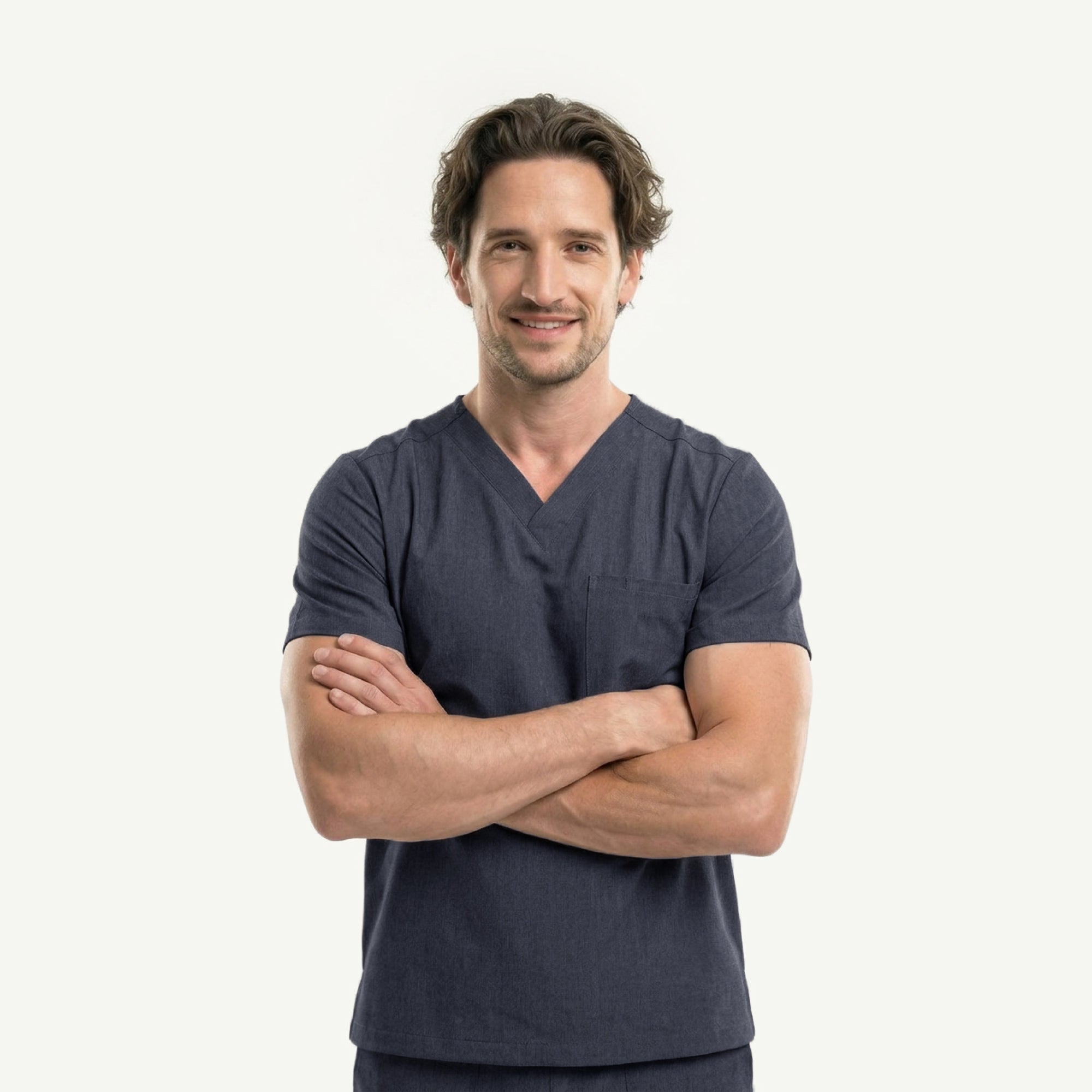 Image of Male healthcare professional in charcoal gray V-neck scrub top and pants, with black stethoscope around neck and hand in pocket, looking to the side,Charcoal-Gray