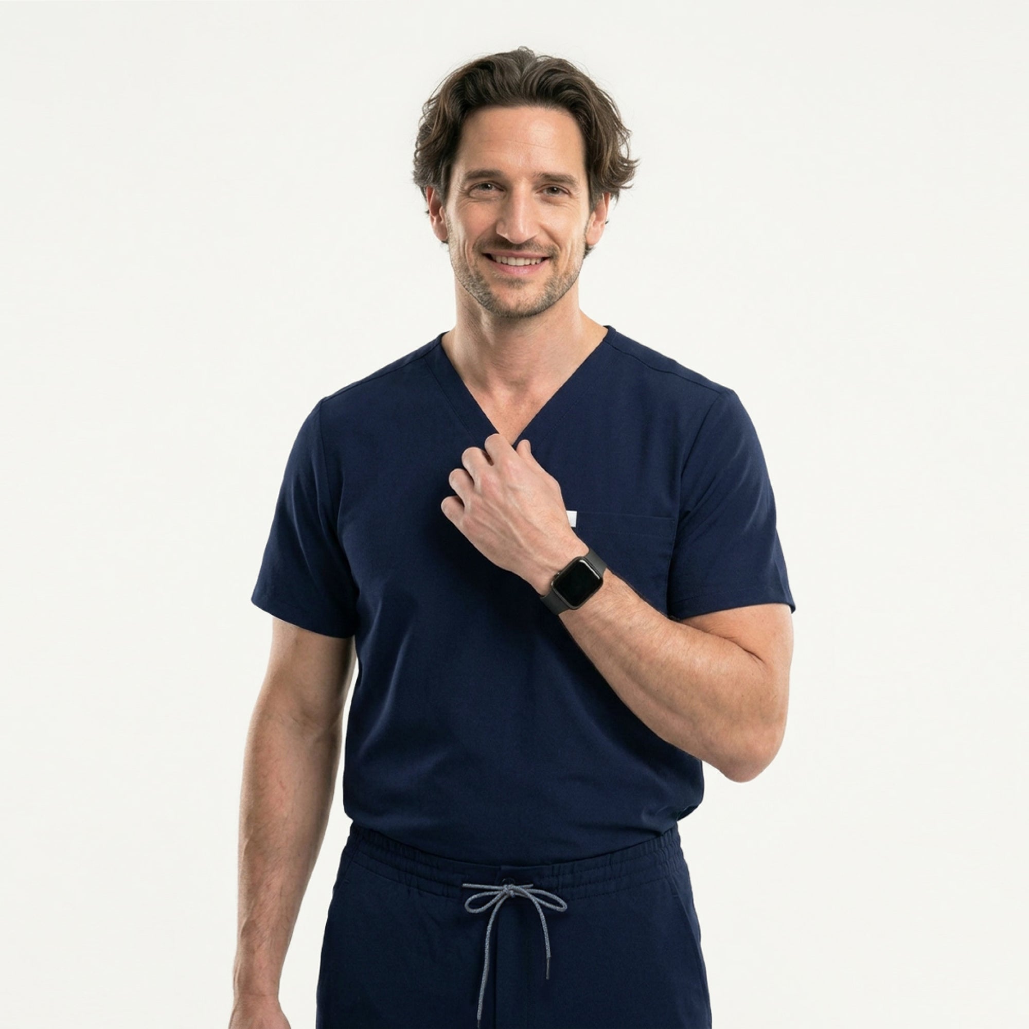 Image of Smiling warmly, the model takes a step ahead in the Eco Navy Single Pocket Scrub Top, arms moving gently with the rhythm of his walk.