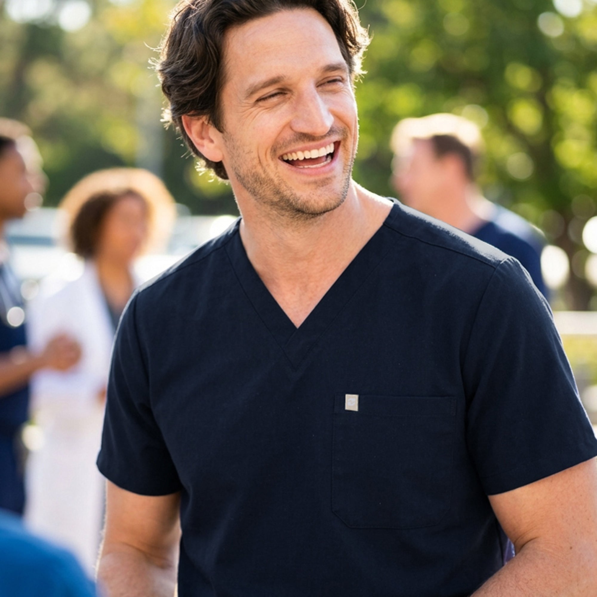 Image of In this front-facing shot, the Eco-Navy single-pocket scrub top displays its simple one-pocket layout, polished V-neckline, and sleek, breathable fabric as the wearer casually interacts with the pocket.
