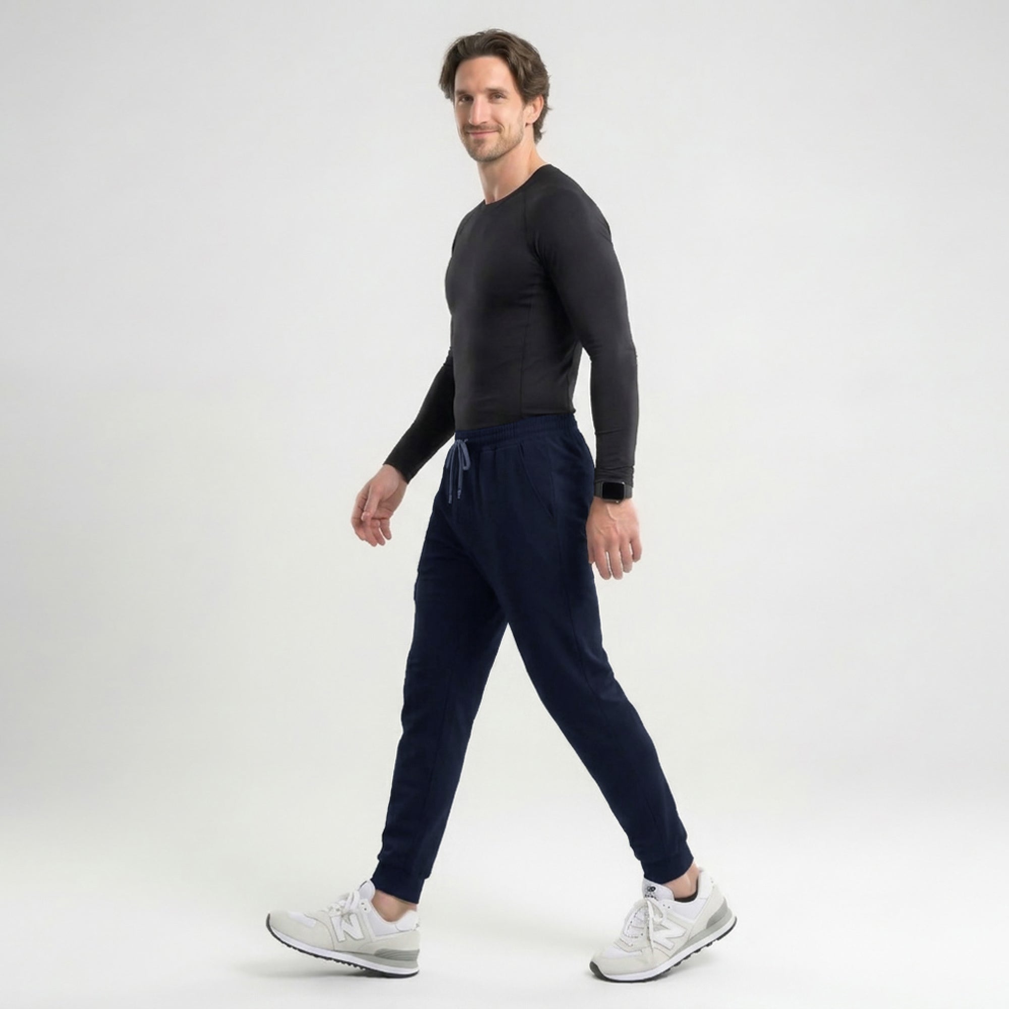 Image of Model wearing navy jogger scrub pants with a zipper pocket and drawstring waist, paired with a matching V-neck scrub top and carrying a black bag,Eco Navy