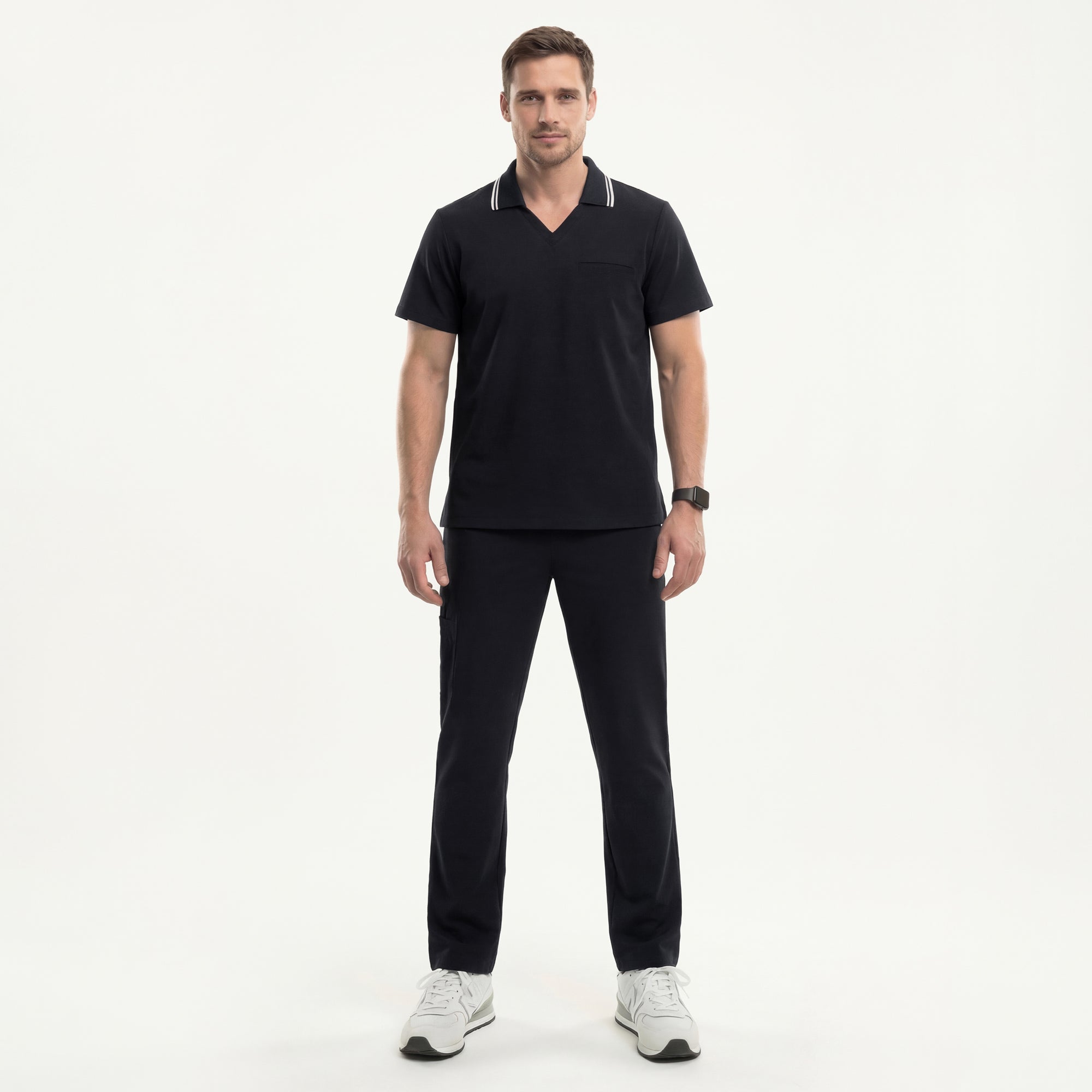 Image of Male model wearing a jet black performance polo scrub top with a striped collar and matching pants, standing straight with sneakers,Jet Black