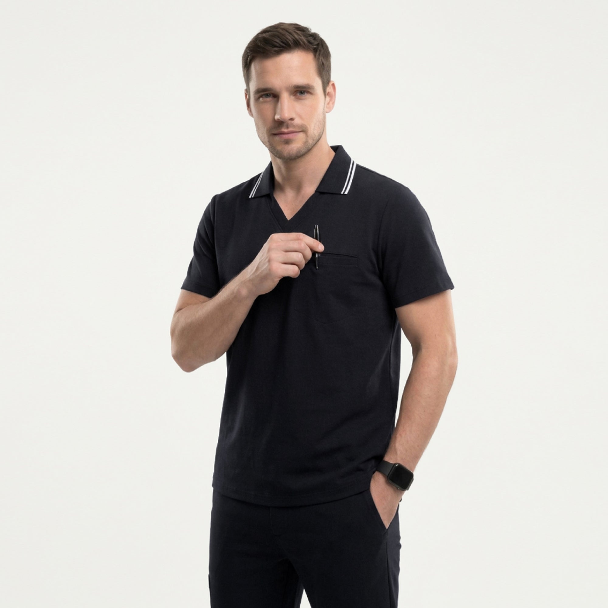 Image of Side profile of a male model wearing a jet black performance polo scrub top with a striped collar and hands in pockets,Jet Black