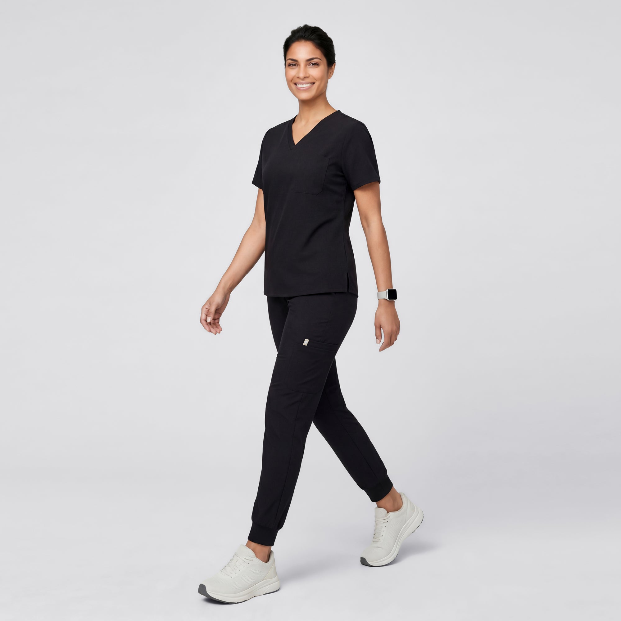 Image of Model wearing Eco Black 3 Pocket Scrub Top, shown from the side while walking.
