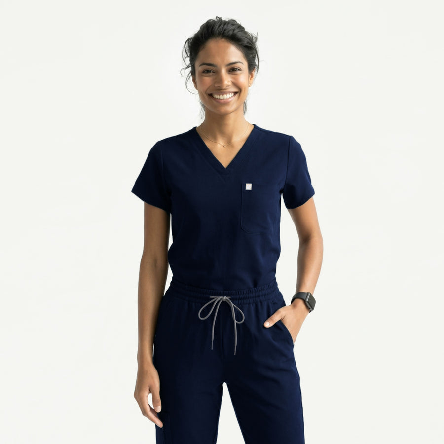 Navy scrub top with single pocket paired with matching scrub pants, holding a red stethoscope with a watch,Eco navy