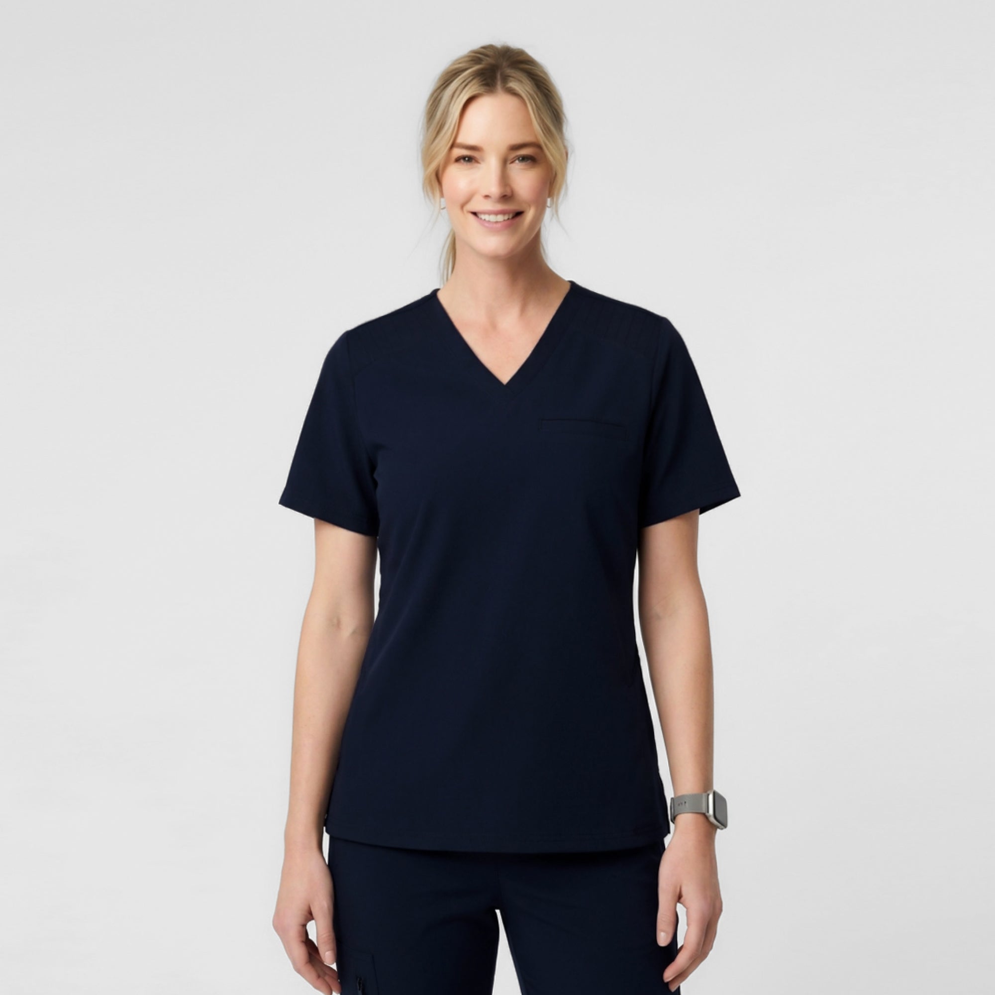 Image of A Female model wearing Eco Navy ZenFlex scrub top with matching scrub pants.