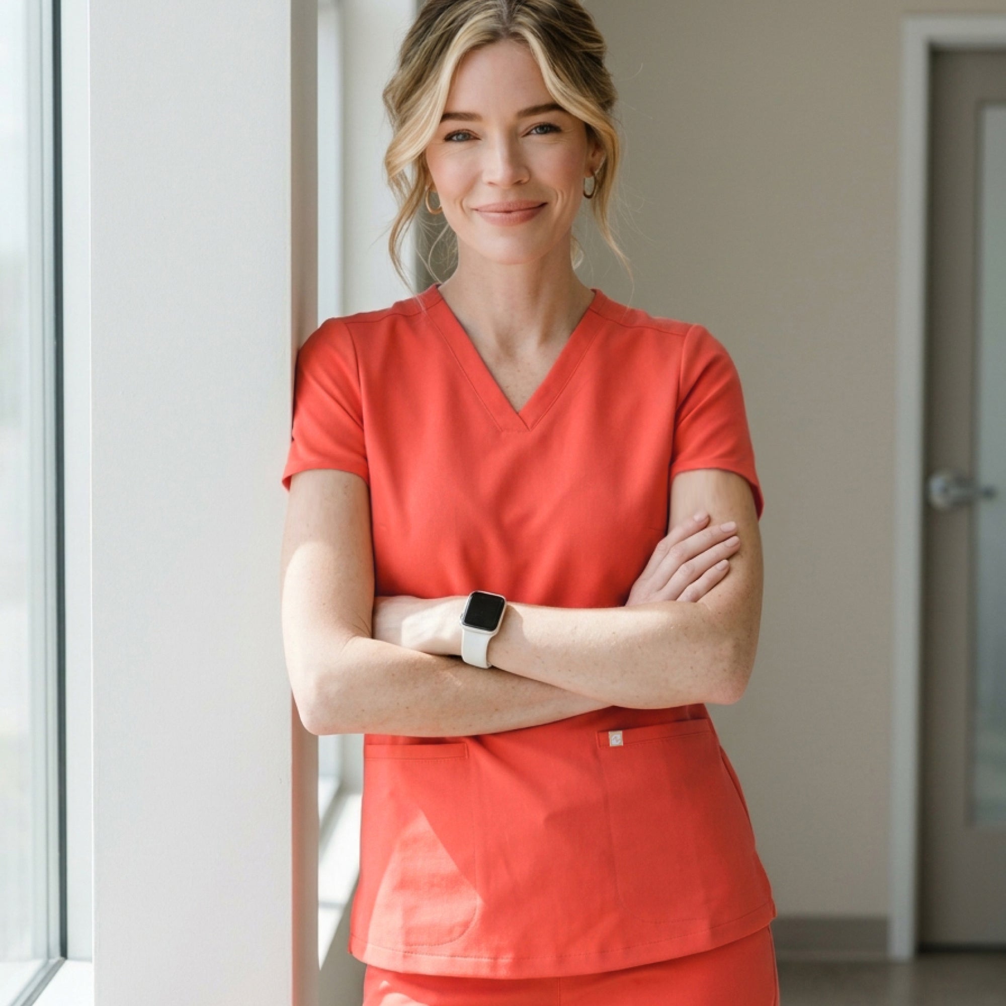 Image of Model dressed in the Women's Tiger Orange Double Pocket Scrub Top, facing forward with a slight smile, upper body shot