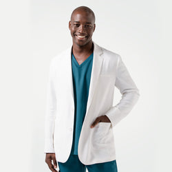 Image of Wearing the Men's LCM-102 Lab Coat in White over medical scrubs, smiling confidently with one hand in the pocket, upper body view