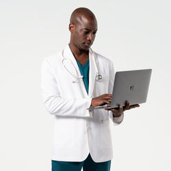 Image of Using a laptop in the Men's LCM-102 Lab Coat in White over medical scrubs, stethoscope draped around the neck, upper body view