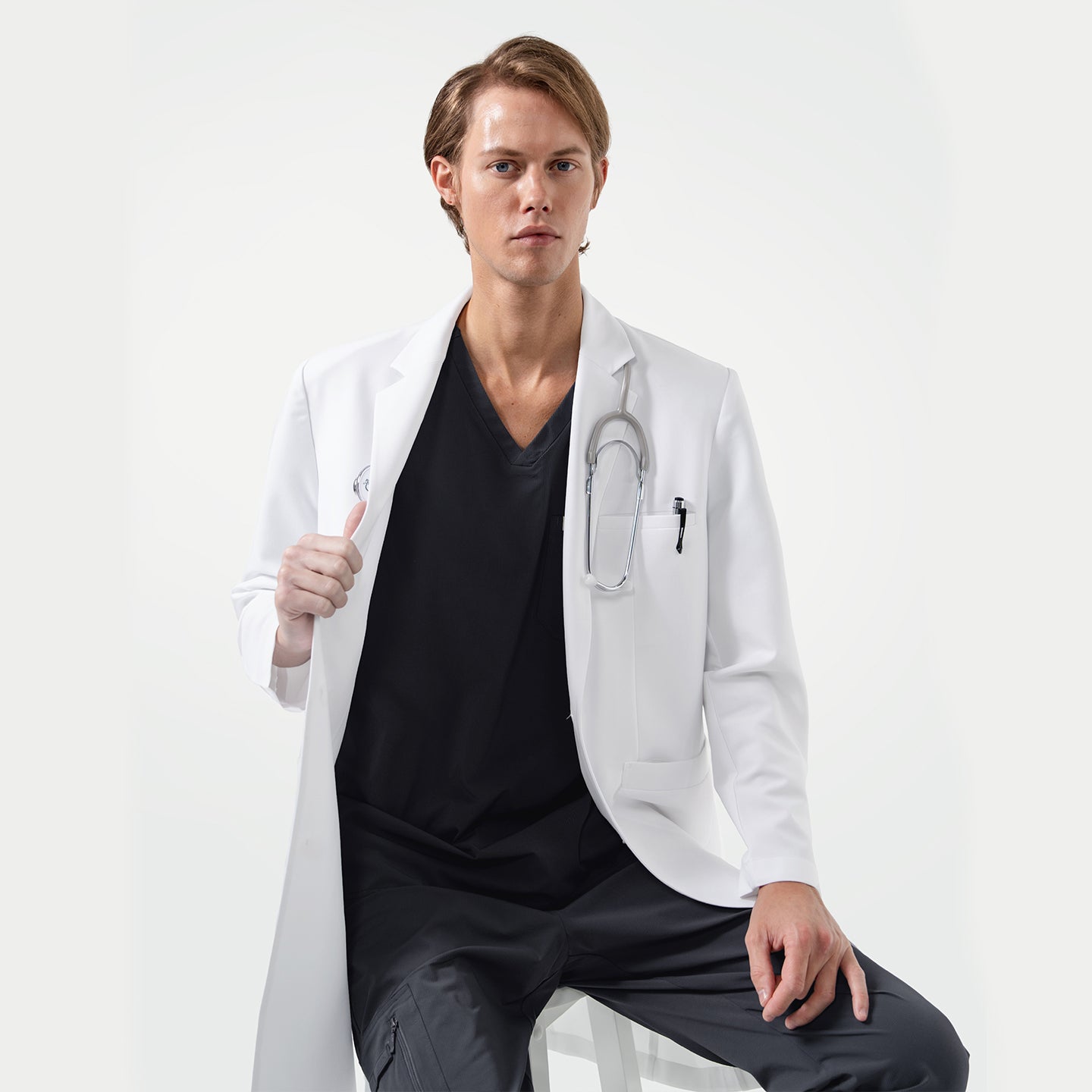 Image of Lcm-103 men’s white lab coat with stethoscope, worn over black scrubs, professional medical uniform.