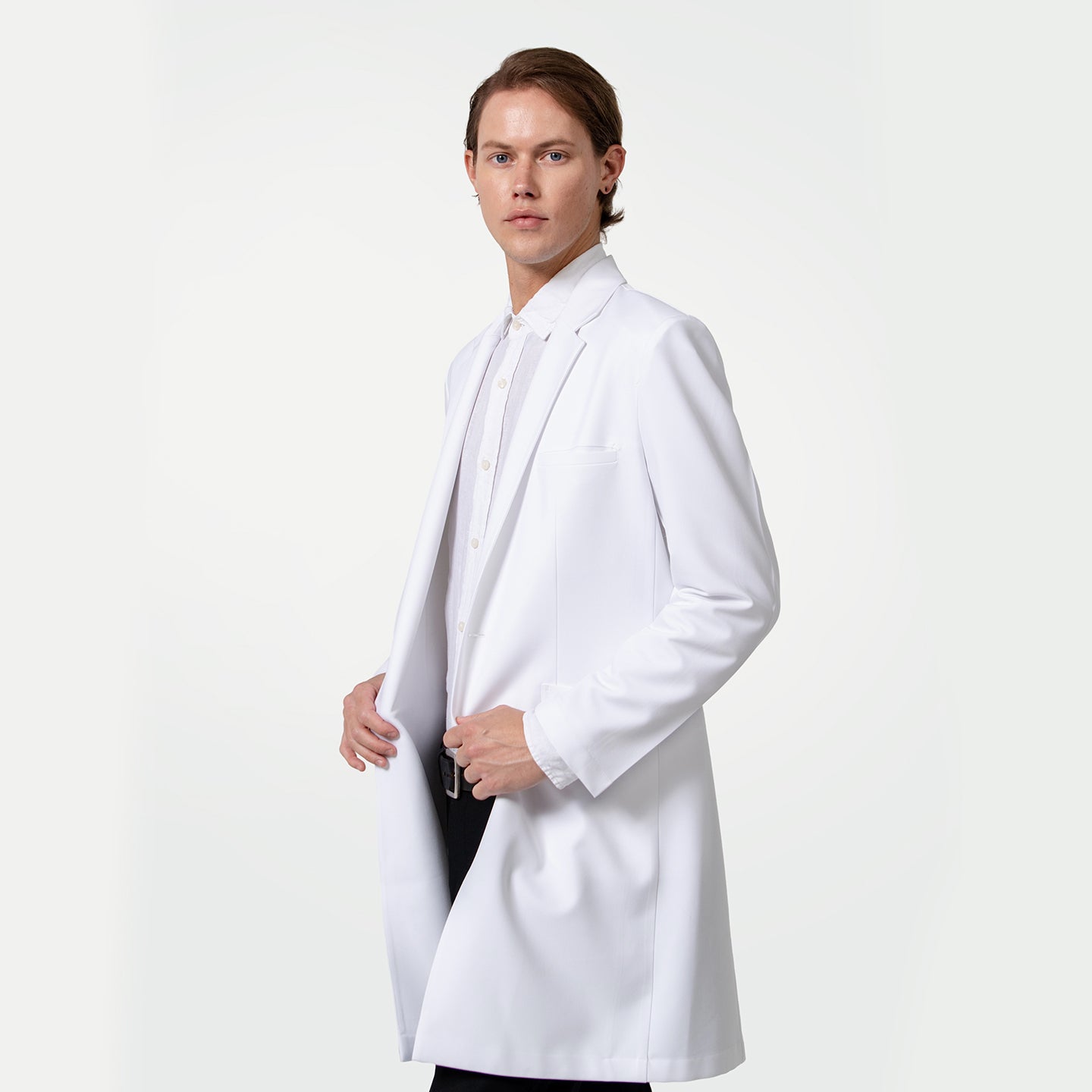 Image of With a composed expression, a male healthcare professional wears a white coat over a white dress shirt and black trousers