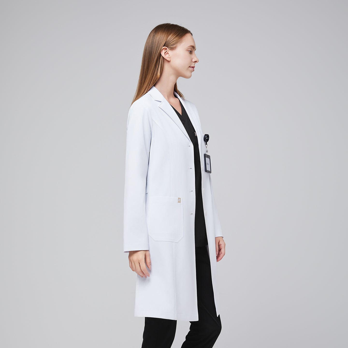 Model facing sideways, with a white long lab coat and black scrub top, and black scrub pants,White