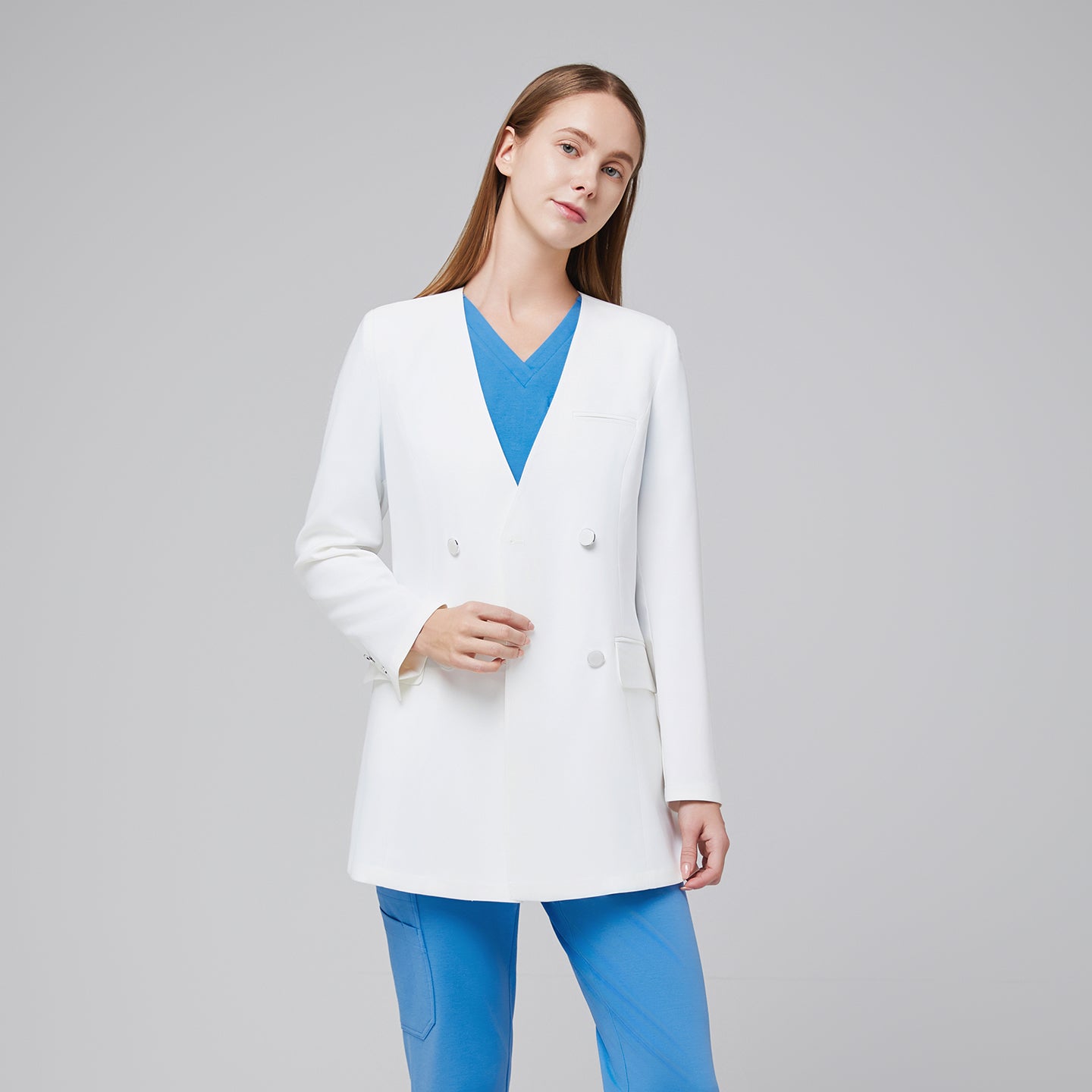 Image of Close-up front angle of a white double-breasted lab coat worn over a blue scrub set, highlighting the coat’s notched collar and button detailing,White