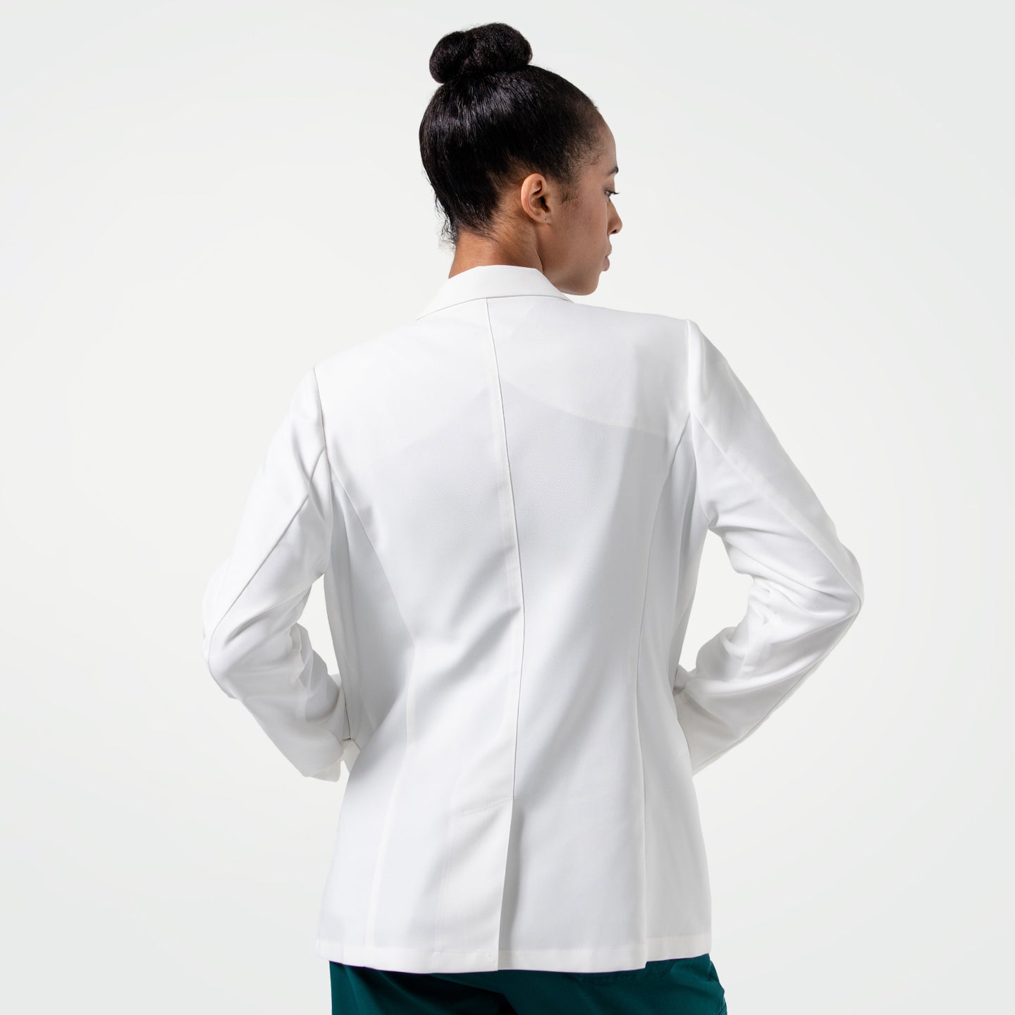 Image of Upper body shot of the model turned around, wearing the Women's LCW-101 Lab Coat over pine green scrubs, looking slightly to the side