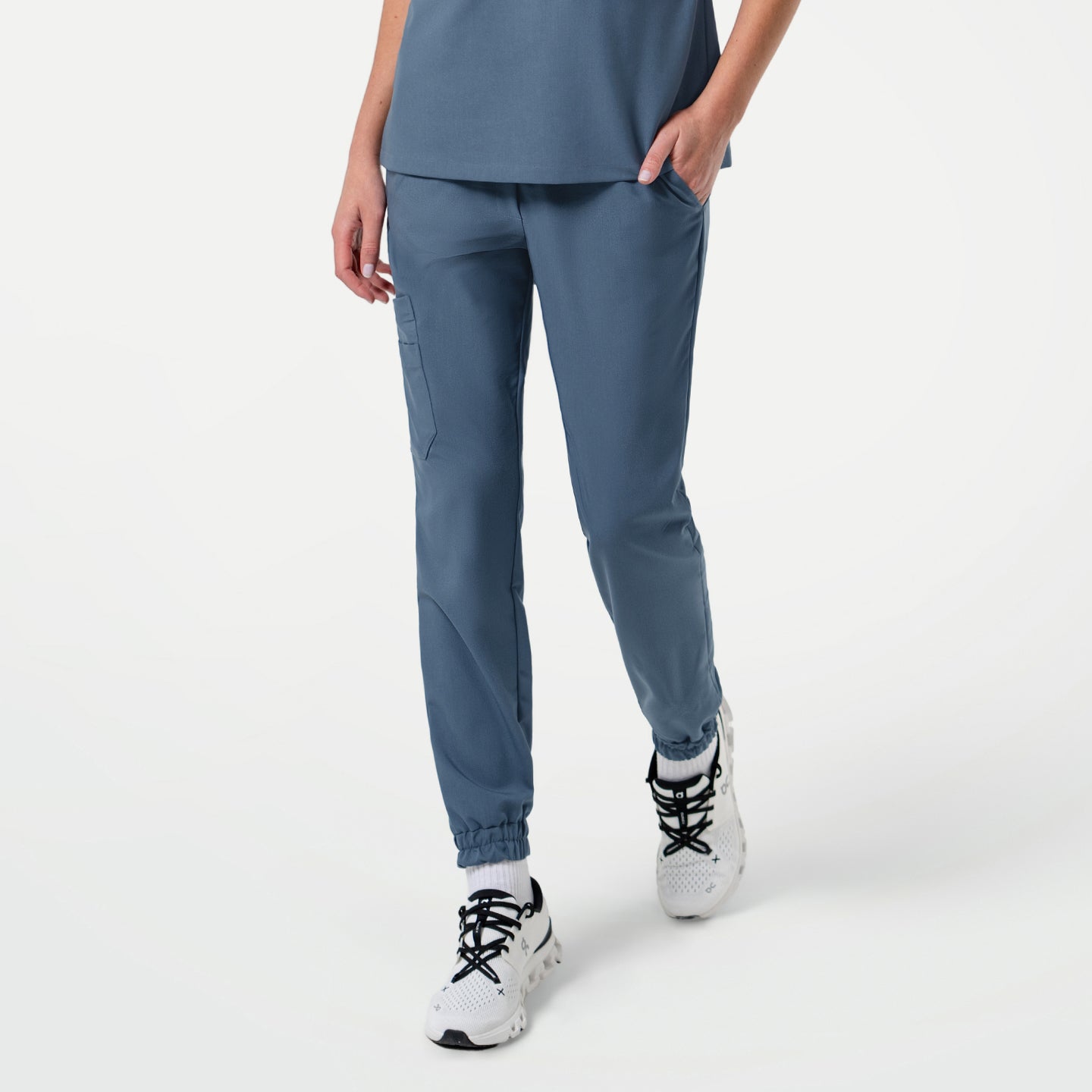 Image of Front view of a person wearing StretchFit Jogger Scrub Pants in Smoky Blue, standing with one hand in the pocket and legs slightly apart.