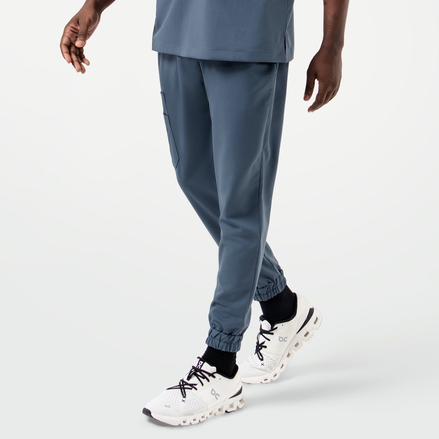Image of Close-up of the model wearing the StretchFit Jogger Scrub Pants in Smoky Blue while taking a step forward.