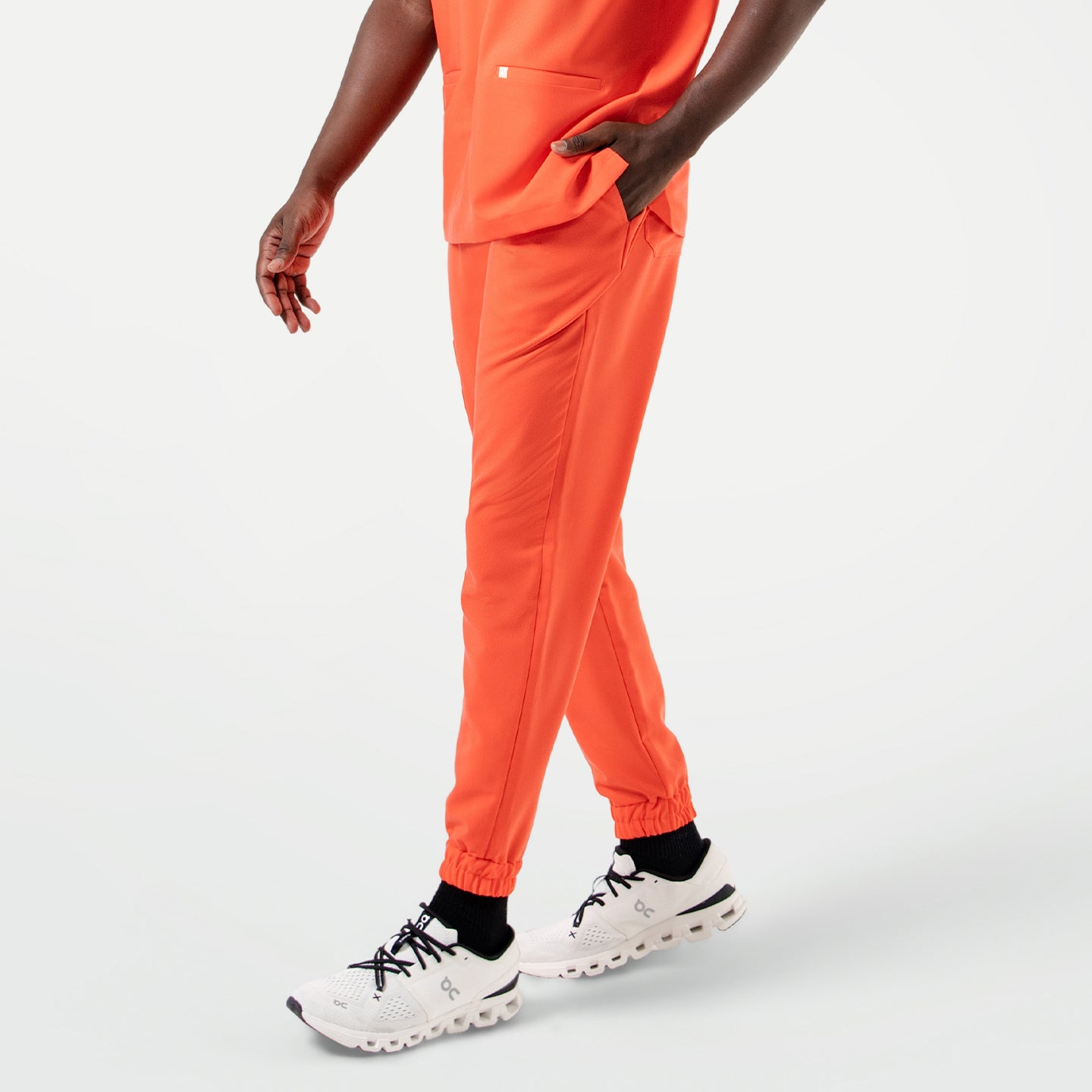 Image of Close-up view of the StretchFit Jogger Scrub Pants in Tiger Orange as the model walks forward.