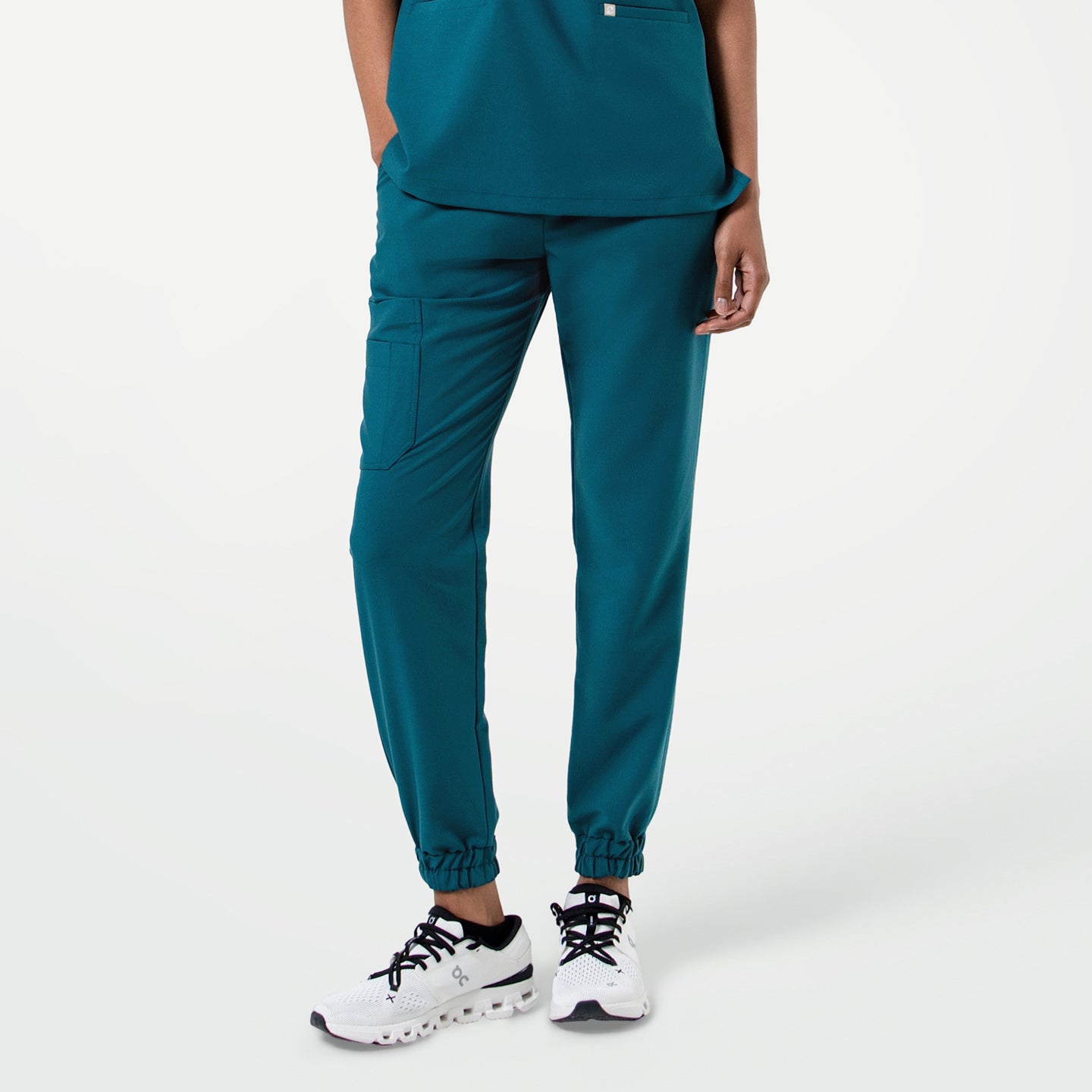 Person wearing StretchFit Jogger Scrub Pants in Ocean Teal, standing with legs slightly apart and one hand resting in the pocket.