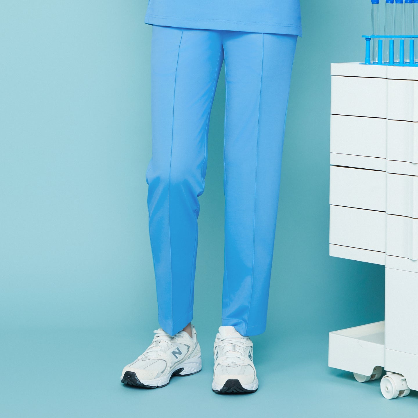 Image of Set against a cool-toned background, the Aqua Blue Premium Banding Scrub Pants highlight their crisp center seam and refined tailoring.