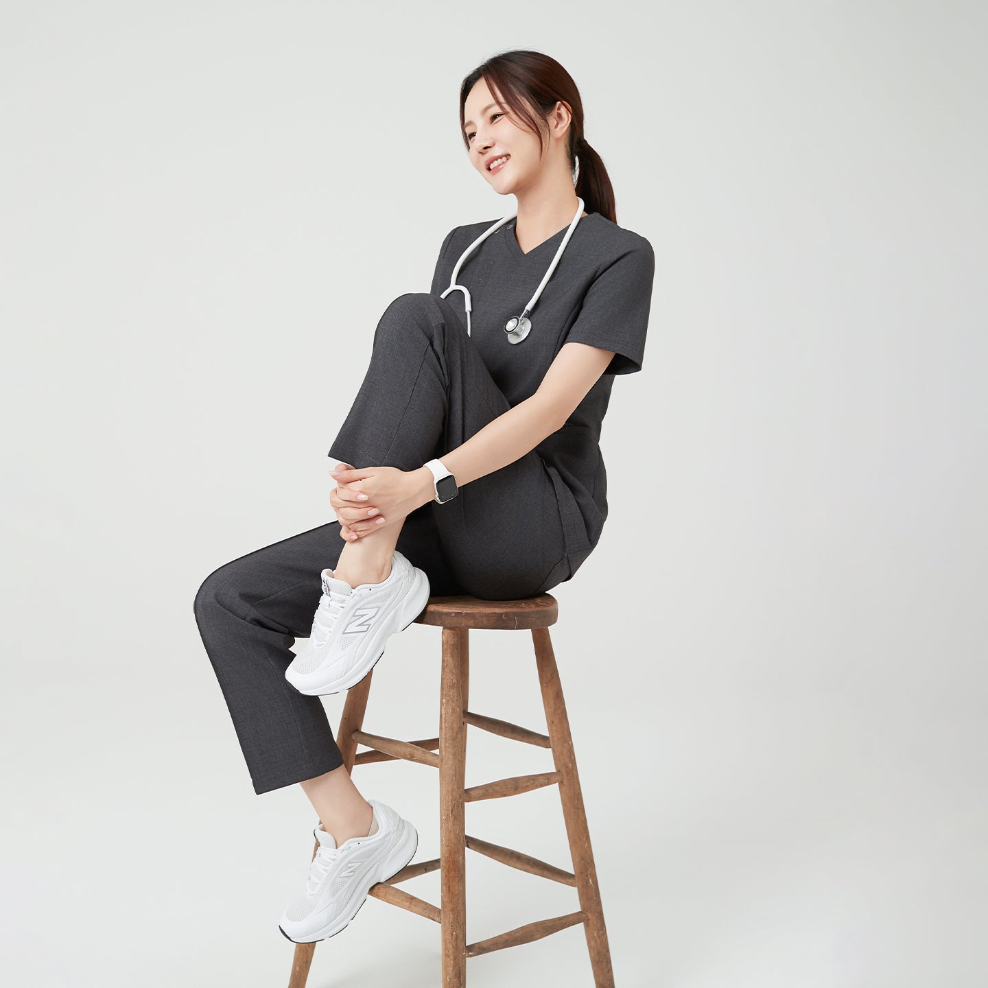 Image of Sitting casually on a stool, the model in Charcoal Gray OS-228 exudes ease and confidence, showcasing the scrub’s relaxed yet refined fit.