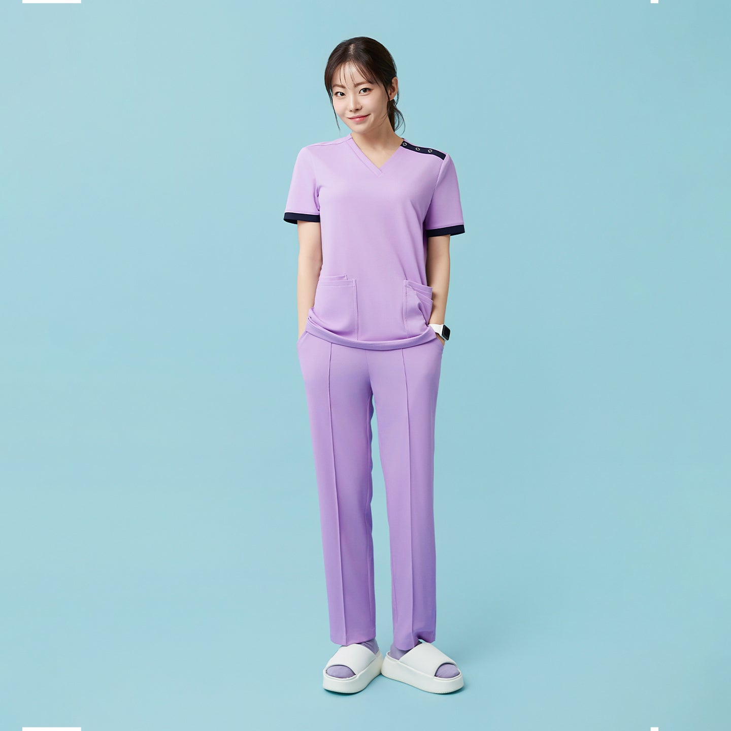 Image of Standing casually with hands in pockets, the model highlights the relaxed fit and natural drape of the Lavender OS-230 scrub set, giving off a clean and comfortable professional look.