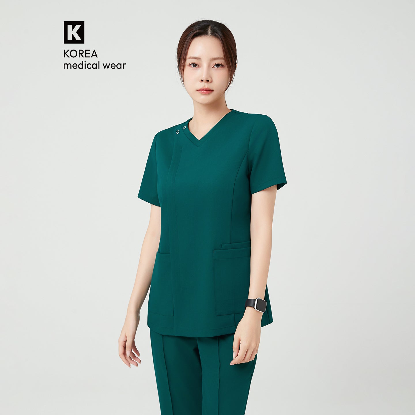 Pine Green OS-225 scrub top presents a clean, structured design with a modern V-neck and subtle front detailing. Deep front pockets add practical functionality, while the fitted cut enhances a sleek, professional silhouette.