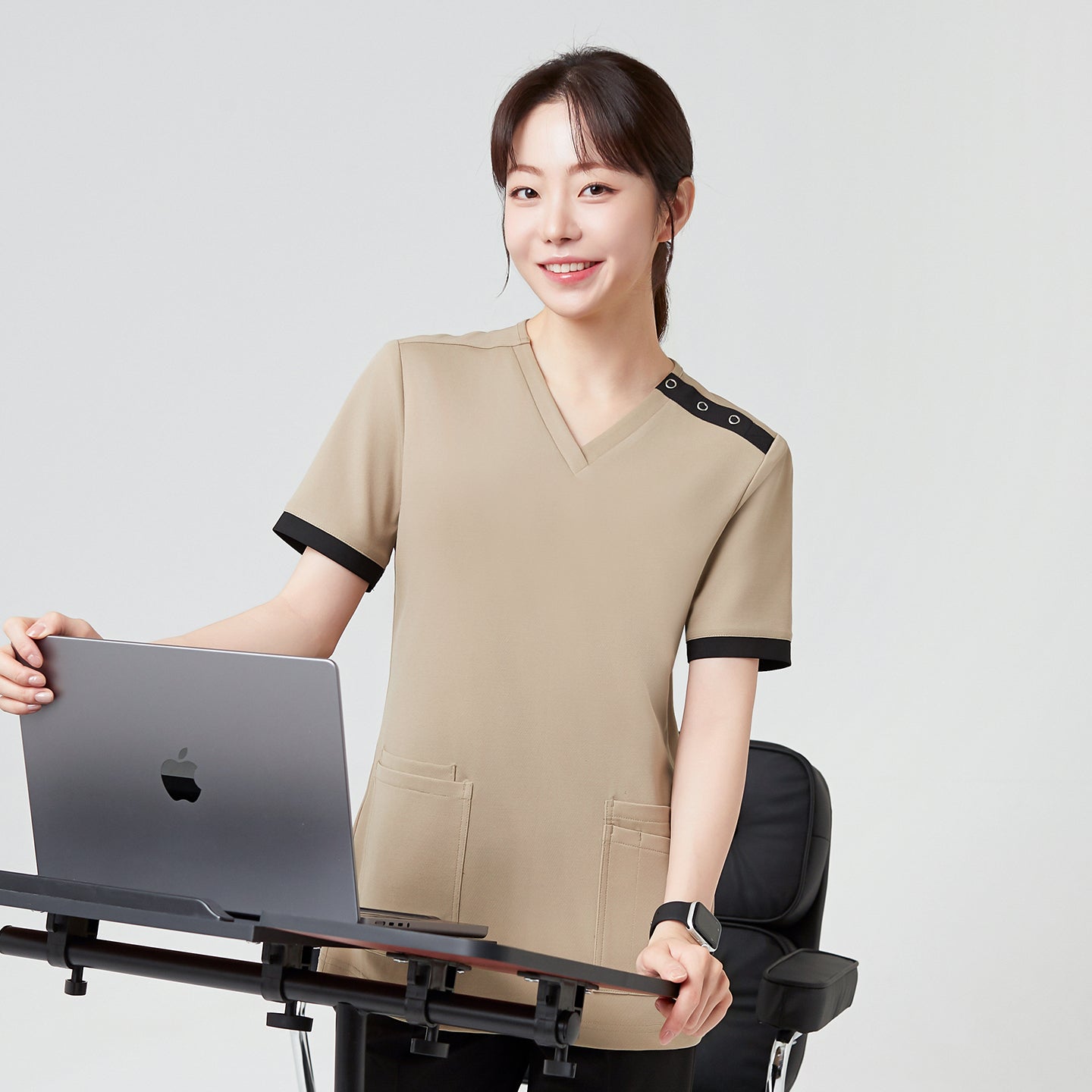Image of Sand Beige OS-229 stands confidently at a desk, showcasing a professional yet approachable look ideal for both clinical and office settings.