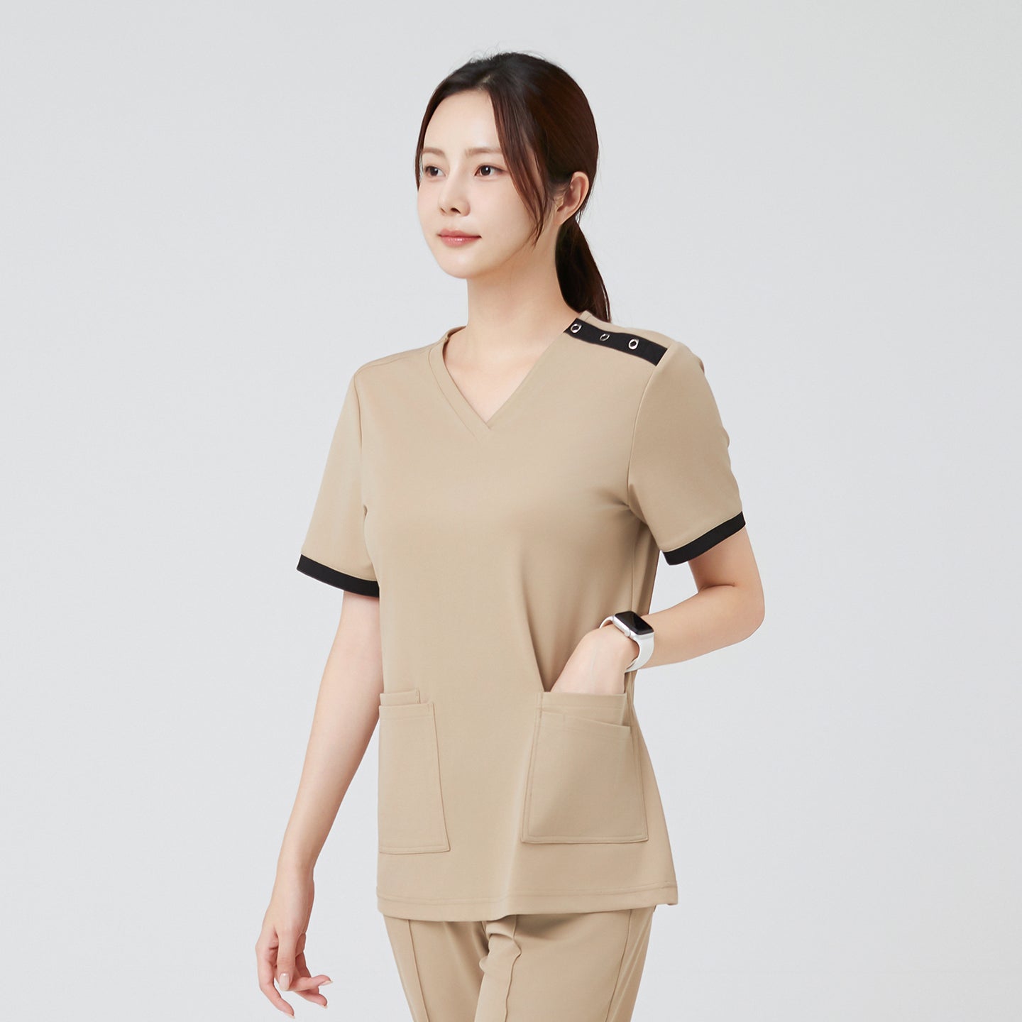 Image of With both hands casually tucked into the pockets, the model in Sand Beige OS-229 showcases the scrub’s practicality and smooth silhouette while maintaining a composed, confident look.