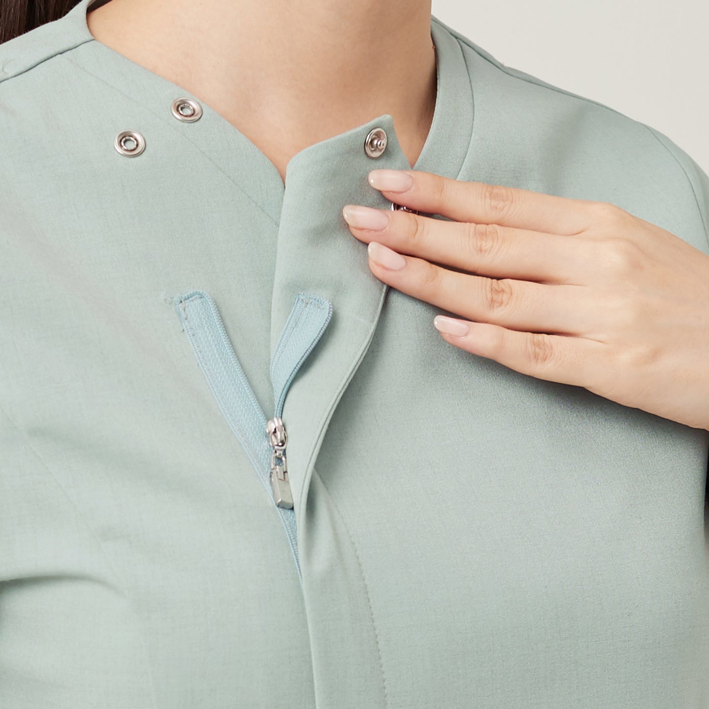 Image of The Soft Mint OS-227 scrub top highlights a clean, polished neckline with a secure snap-button and concealed zipper detail. Its fresh mint tone and smooth texture create a calm, refined look, while the design ensures both ease of wear and a professional finish.