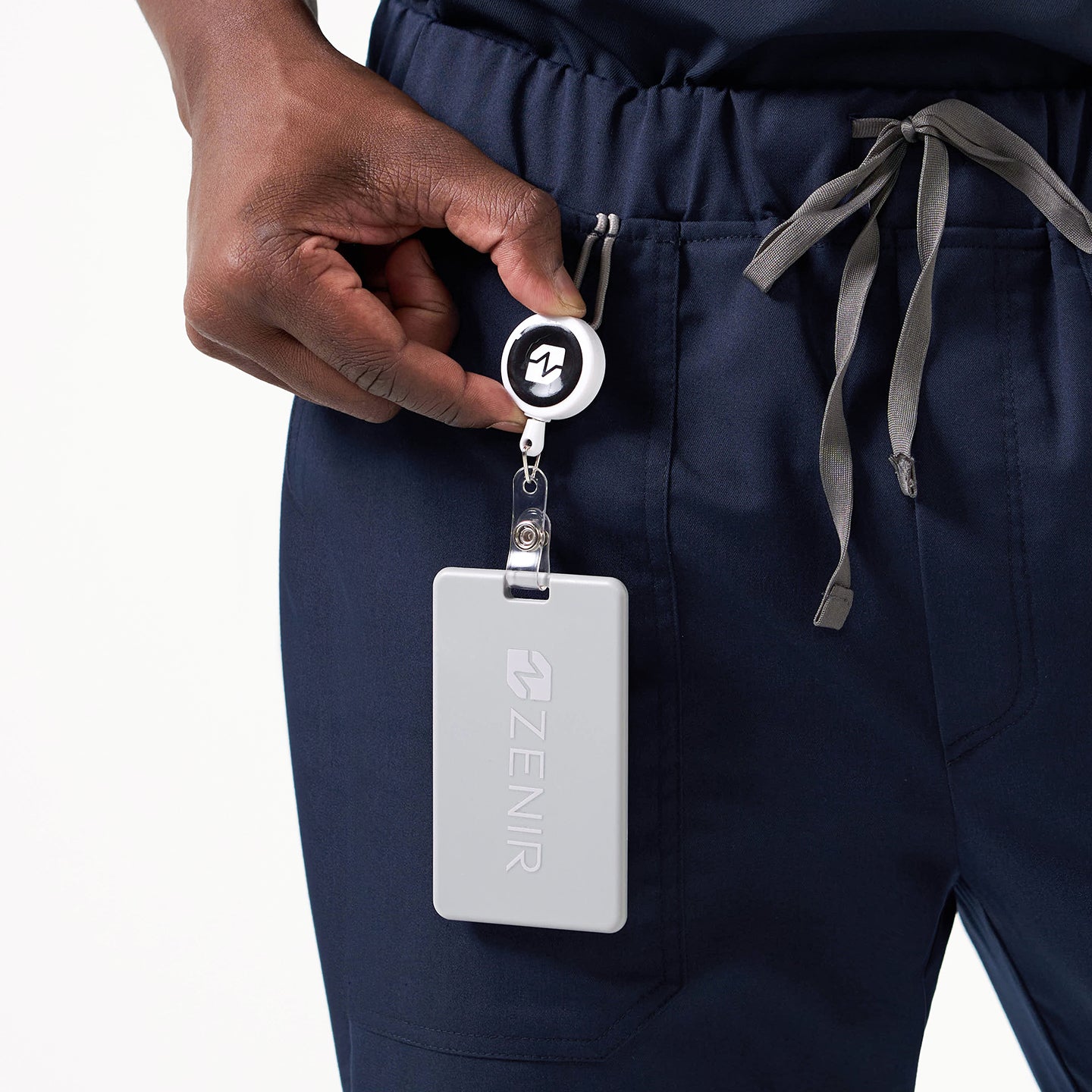 Image of Close-up of a person wearing Eco Navy 8-Pocket Straight Scrub Pants, holding a retractable badge reel with a gray ZENIR ID card clipped to the waistband.