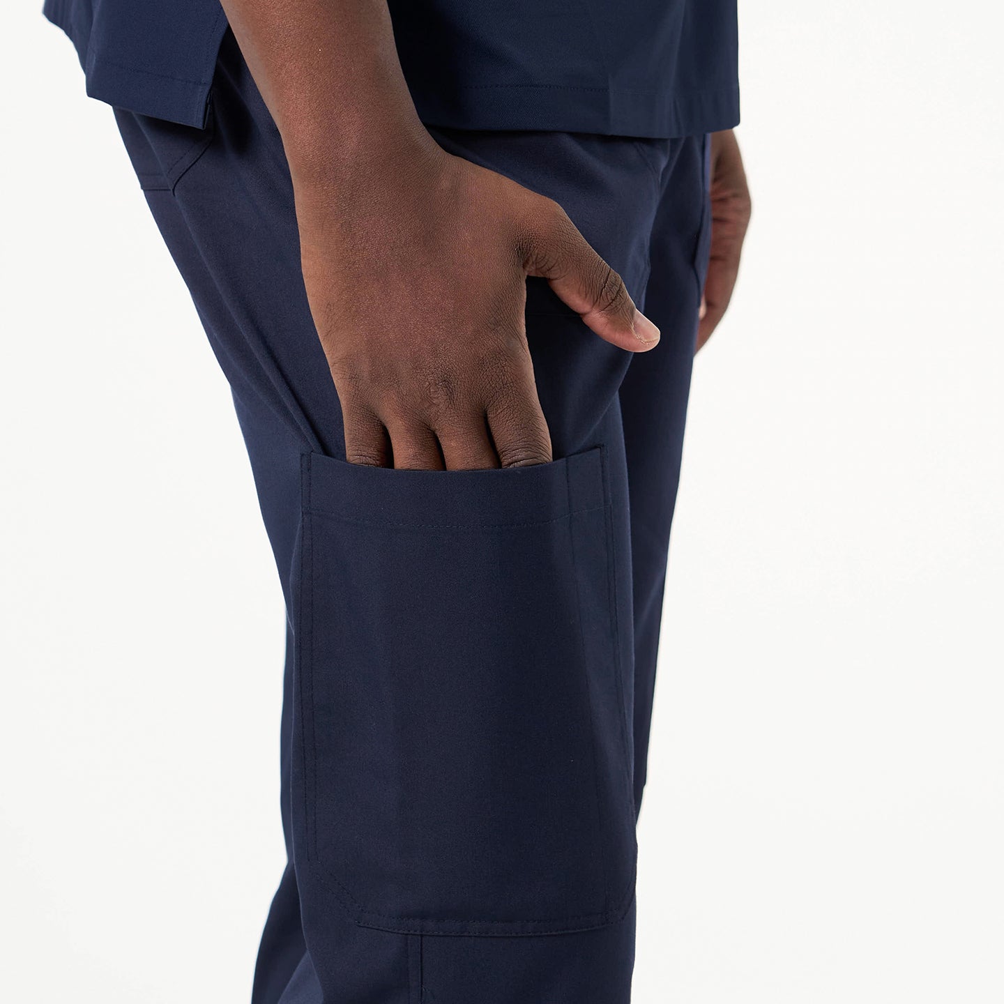 Image of Close-up of a person wearing Eco Navy straight scrub pants, with their hand resting inside the side pocket.