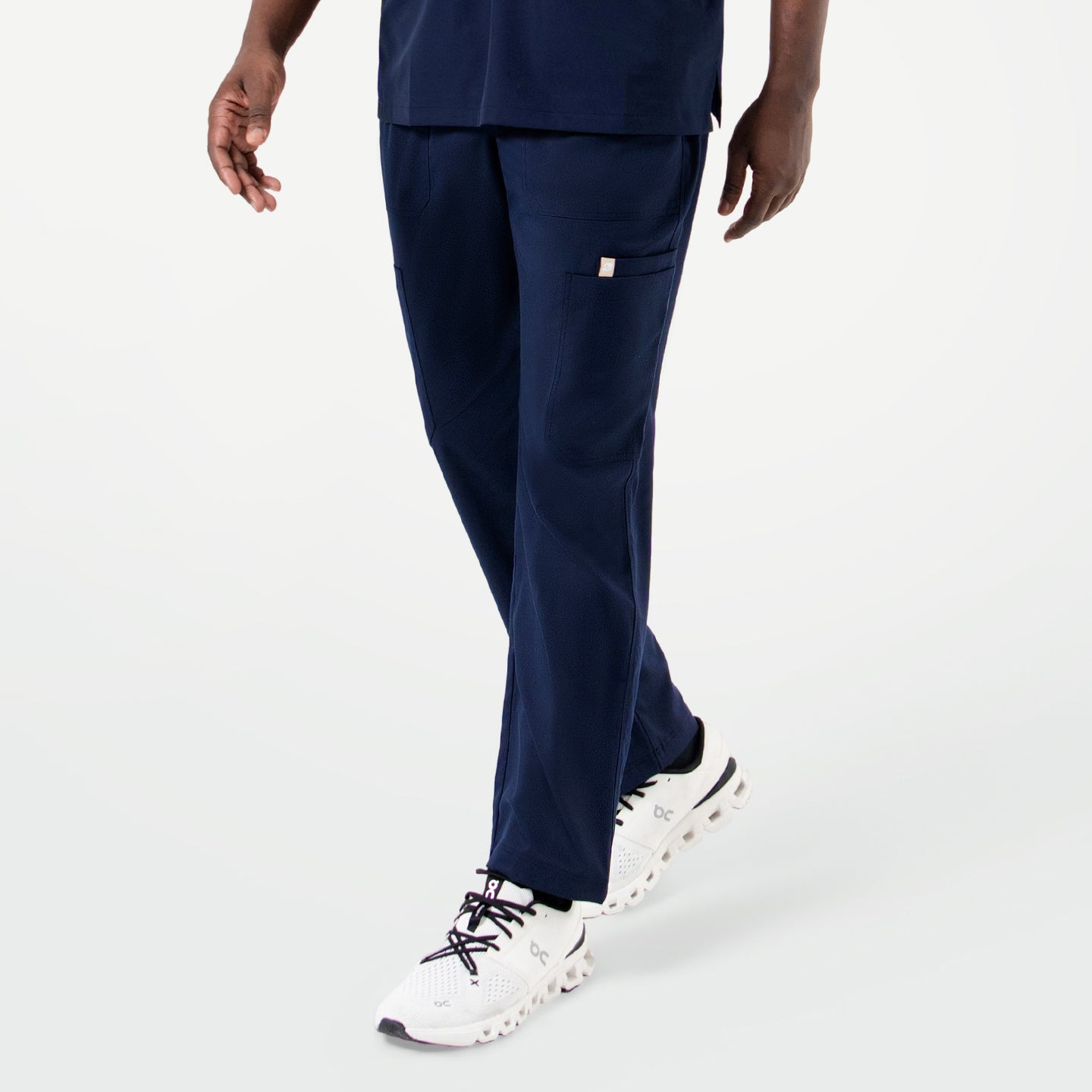 Image of Person walking while wearing Eco Navy 8-Pocket Straight Scrub Pants, showcasing multiple pockets and a relaxed straight-leg fit.