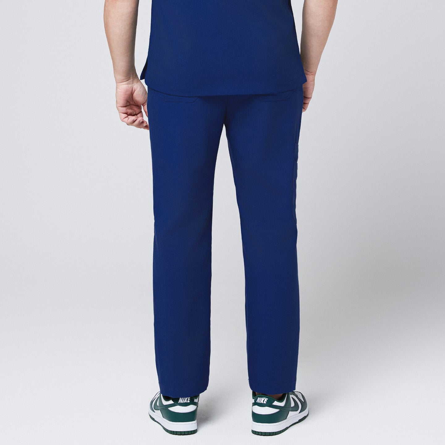 Image of Back view of Zenir Admiral Blue straight scrub pants, featuring a clean design paired with green sneakers for a polished look, Admiral Blue
