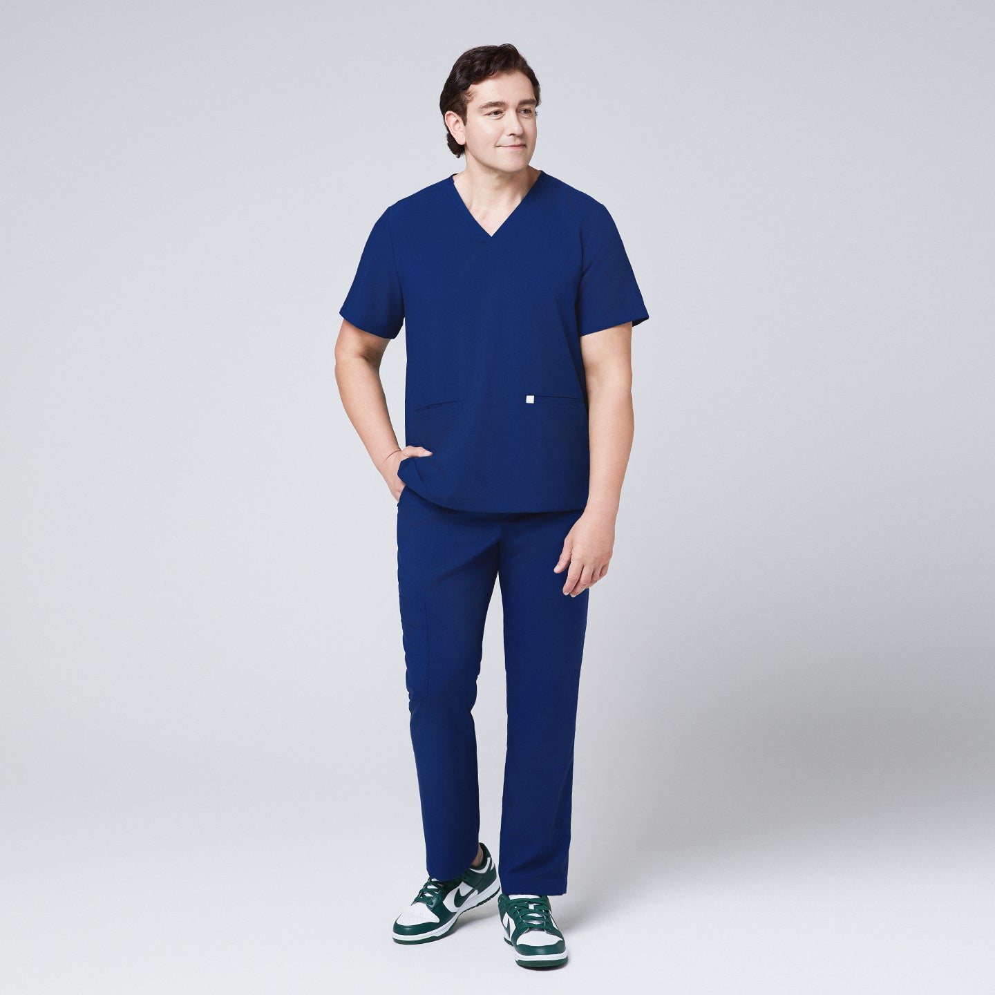 Image of Man in Zenir Admiral Blue scrub top and pants with green sneakers, showcasing a comfortable and professional medical uniform,Admiral Blue