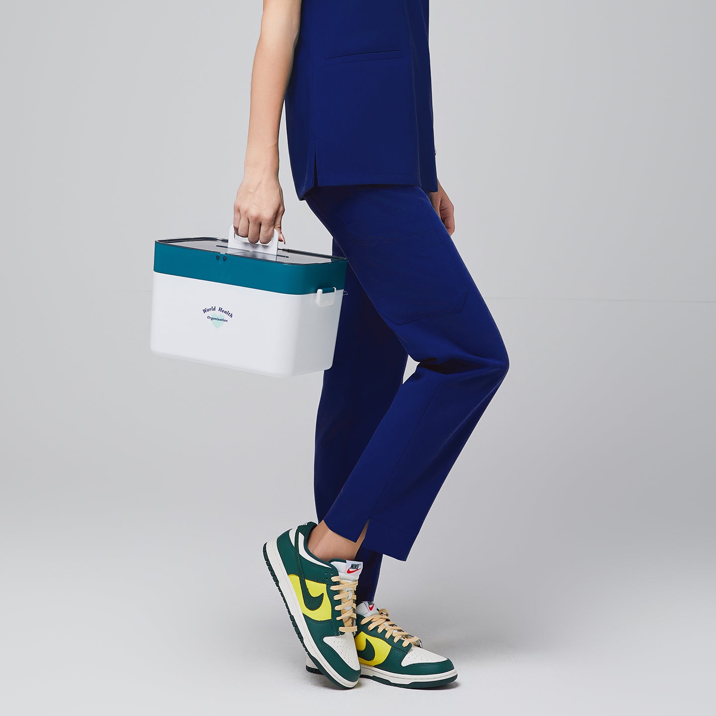 Image of Model wearing an admiral blue scrub pants with a straight fit and split hem for added mobility, with a matching admiral blue scrub pants with a medical box in hand,Admiral blue