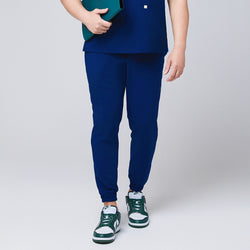 Image of Front view of Zenir Admiral Blue jogger scrub pants with elastic cuffs, paired with green sneakers, showcasing a professional and modern design, Admiral Blue