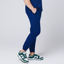 Image of Side view of Zenir Admiral Blue jogger scrub pants with elastic cuffs and a functional pocket, paired with green sneakers for a sleek look, Admiral Blue