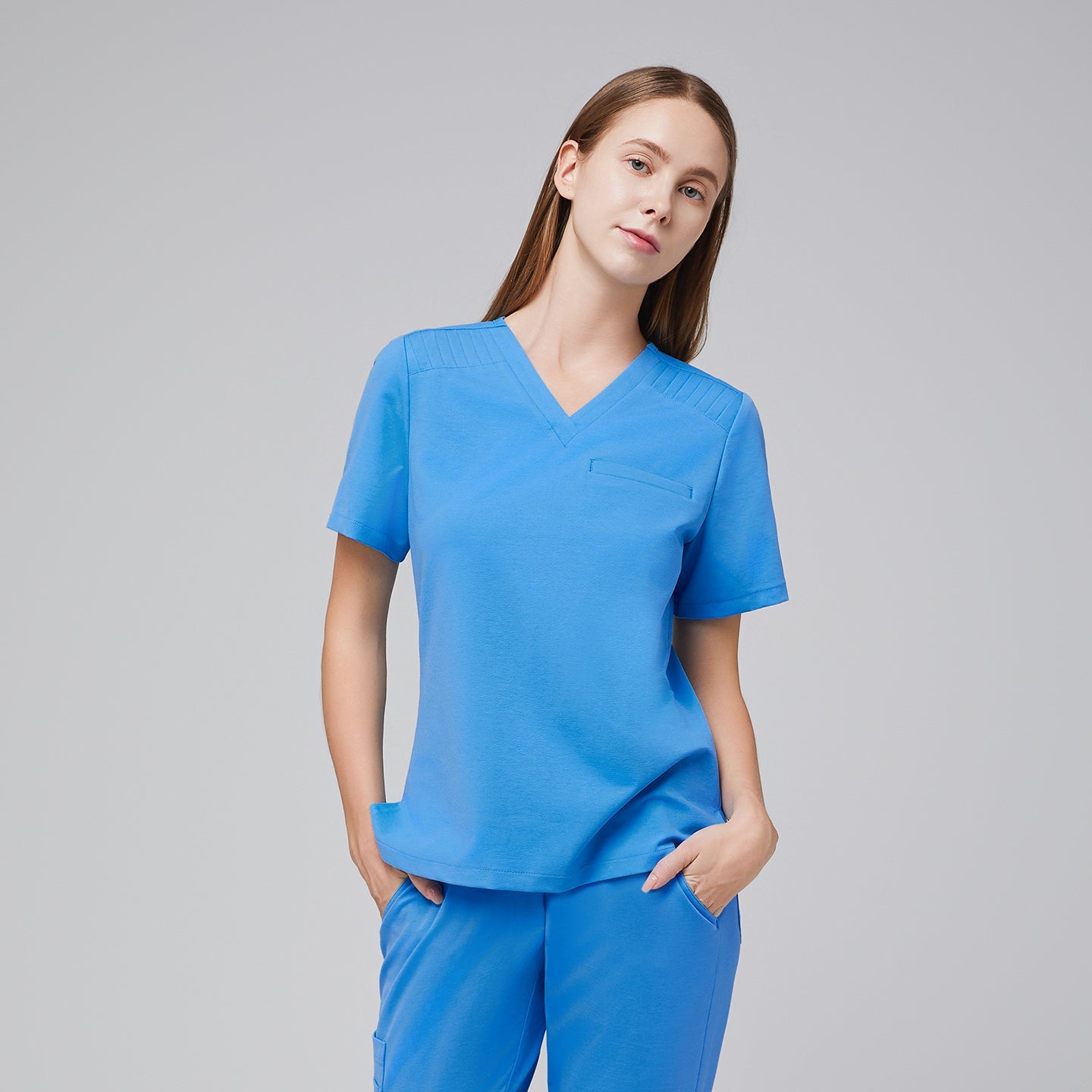 A woman wearing the Aqua Blue Pleated Shoulder Scrub Top with her hands in her pockets,Aqua Blue