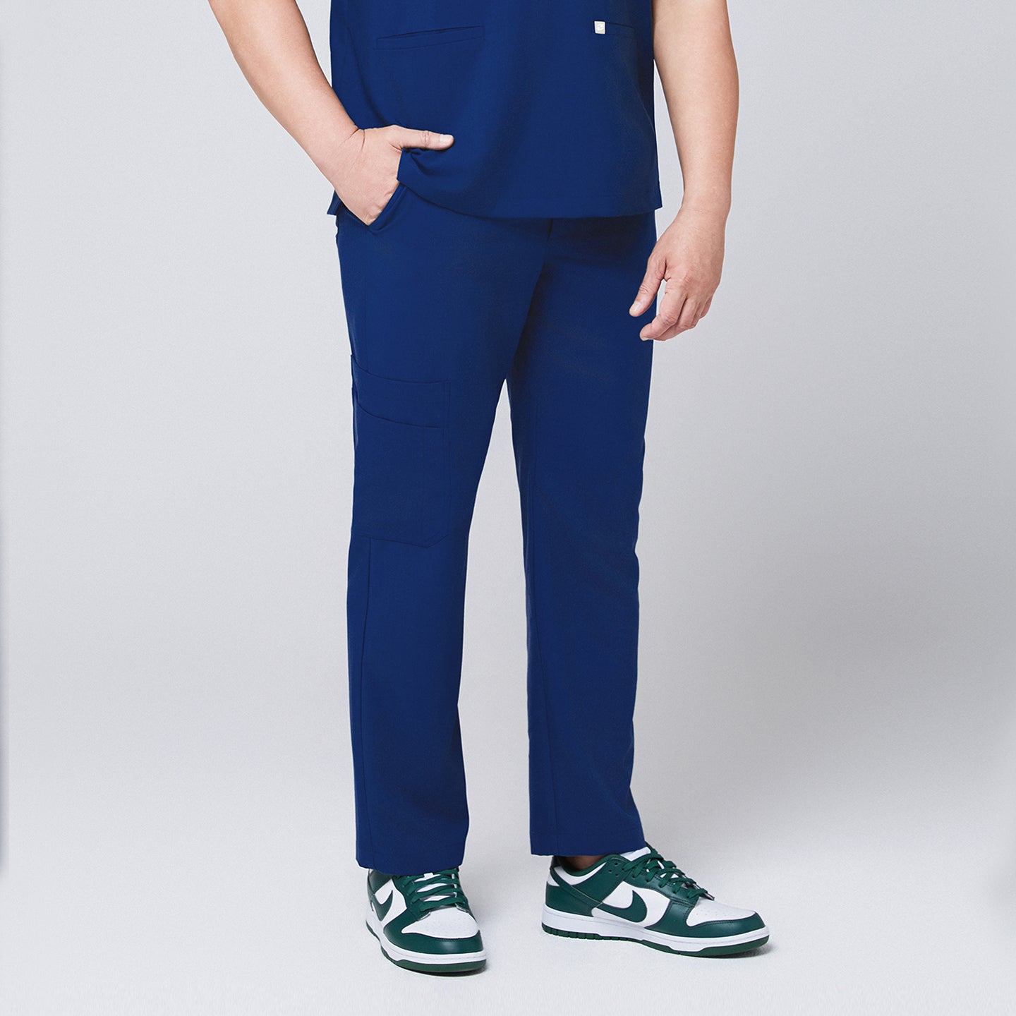 Image of Side view of Zenir Admiral Blue straight scrub pants with a functional pocket, styled with green sneakers for a professional appearanc,Aqua Blue