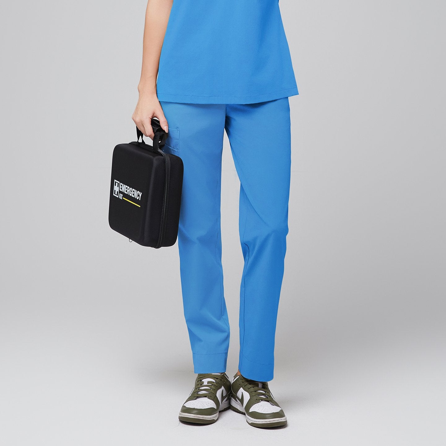 Image of Close-up of a model wearing aqua blue scrub pants ft, holding a black emergency kit against a grey background,Aqua Blue
