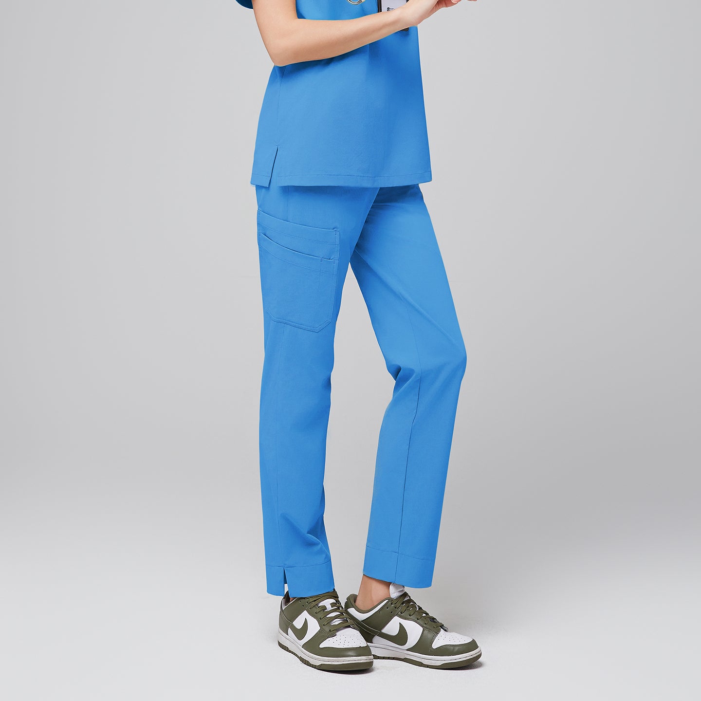 Woman modeling an aqua blue scrub top with matching aqua blue scrub pants with a split hem, featuring multiple pockets and breathable fabric for optimal comfort and functionality in healthcare settings,Aqua blue