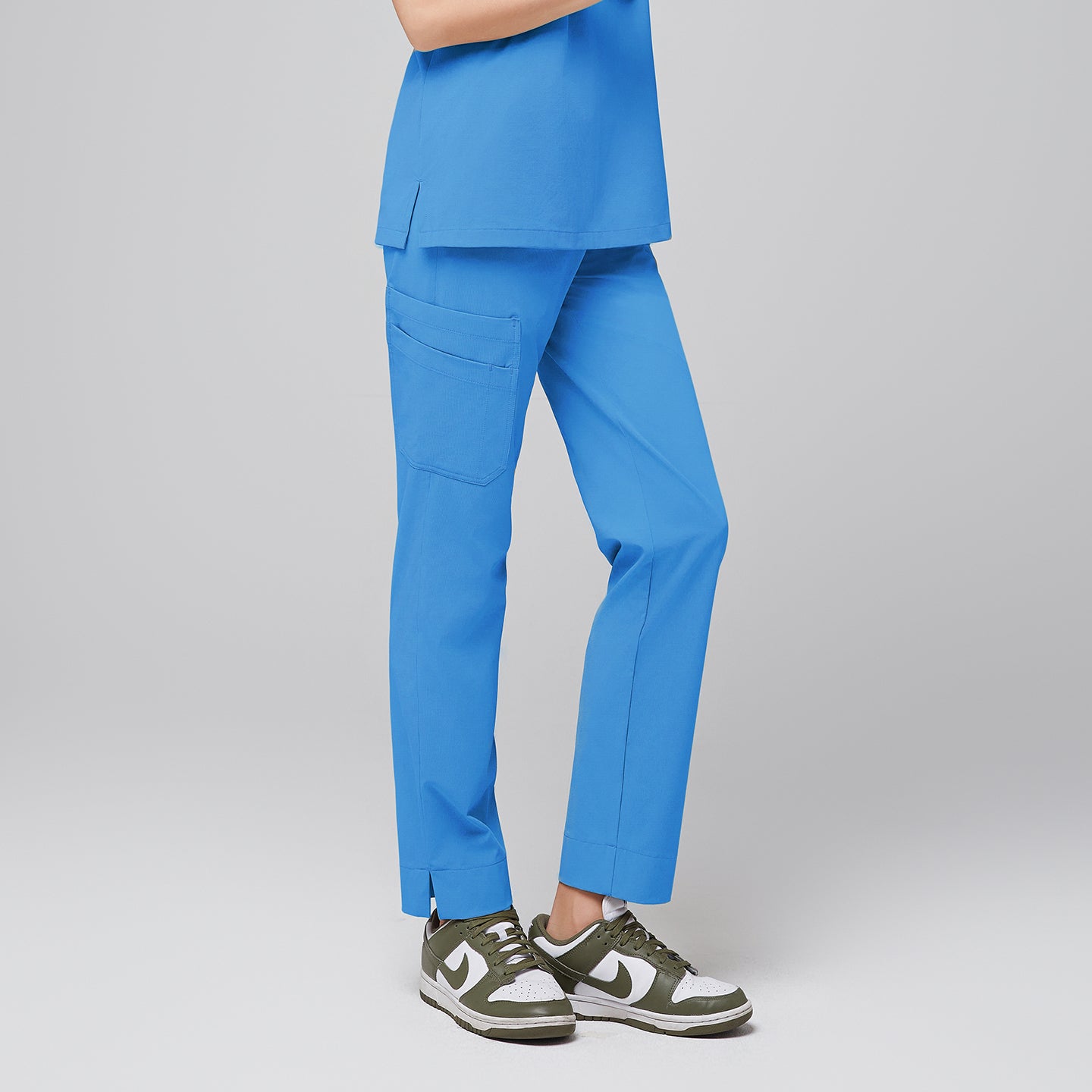Image of Woman modeling an aqua blue scrub top with matching aqua blue scrub pants with a split hem, featuring multiple pockets and breathable fabric for optimal comfort and functionality in healthcare settings,Aqua blue