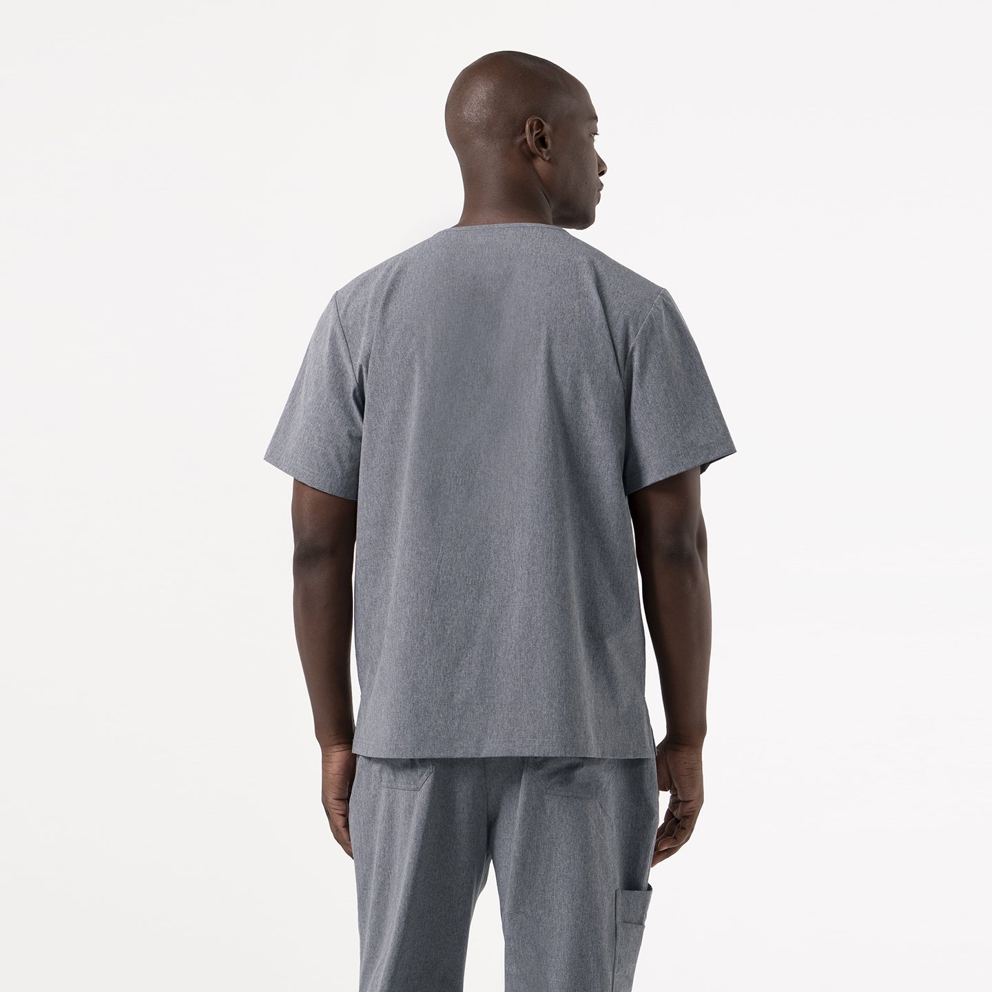 Image of The model shows the back view of the Ash Gray 3 Pocket Scrub Top, standing with arms relaxed at the sides.