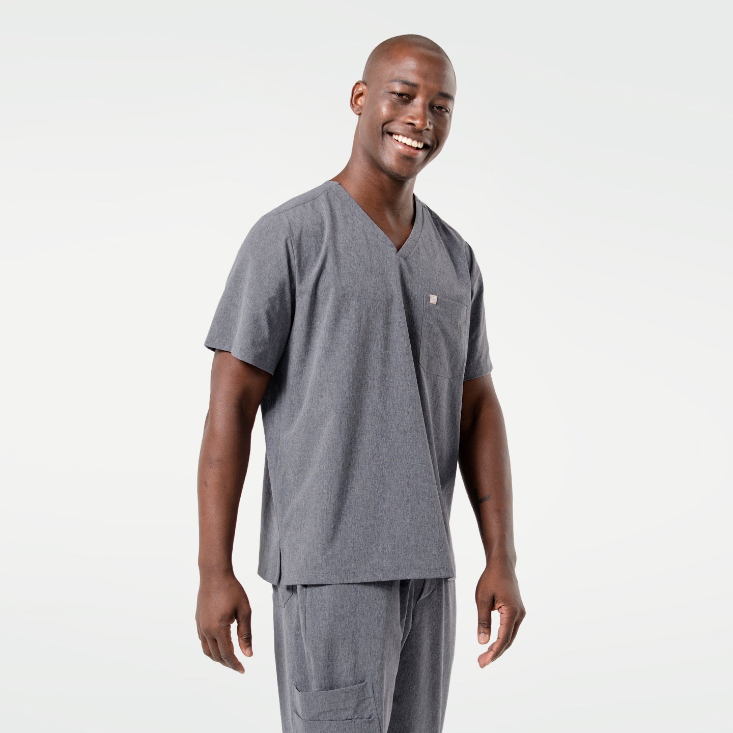 Image of Smiling warmly, the male model stands in an Ash Gray scrub set, highlighting a clean and professional yet approachable look.
