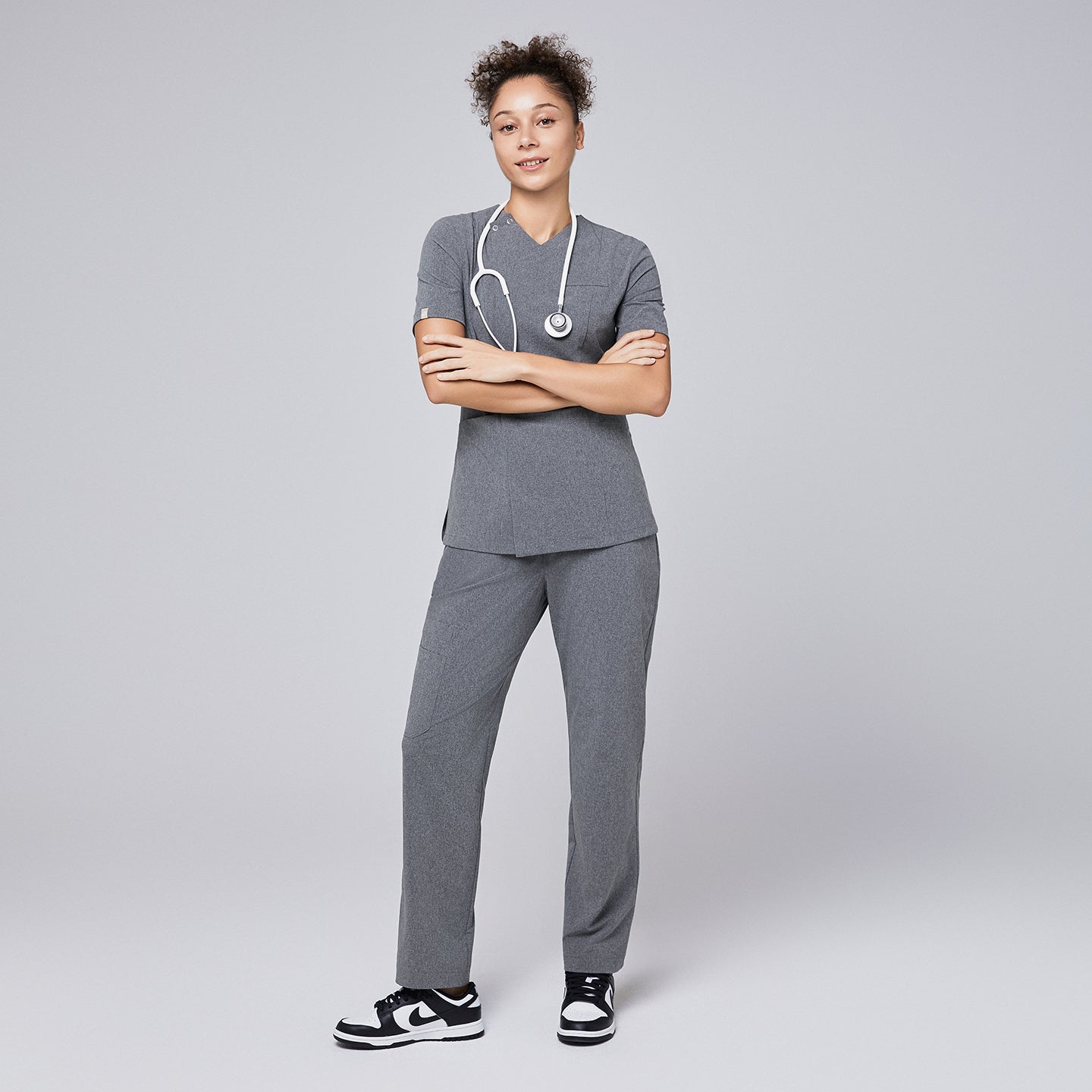Image of Model wearing ash gray straight-leg scrub pants with a split hem, featuring a cargo pocket, paired with black-and-white sneakers on a neutral background,Ash Gray